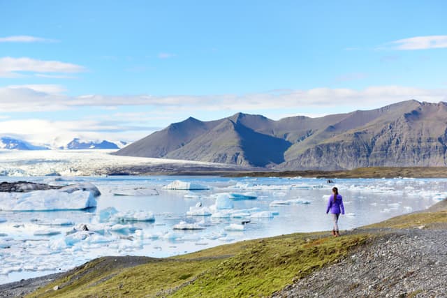 Iceland travel tourist enjoying view of nature landscape Jokulsarlon glacial lagoon / glacer lake on Iceland. Woman outdoors by tourist destination landmark attraction. Vatnajokull National Park. Iceland travel tourist enjoying view of nature landscape Jokulsarlon glacial lagoon / glacer lake on Iceland. Woman outdoors by tourist destination landmark attraction. Vatnajokull National Park