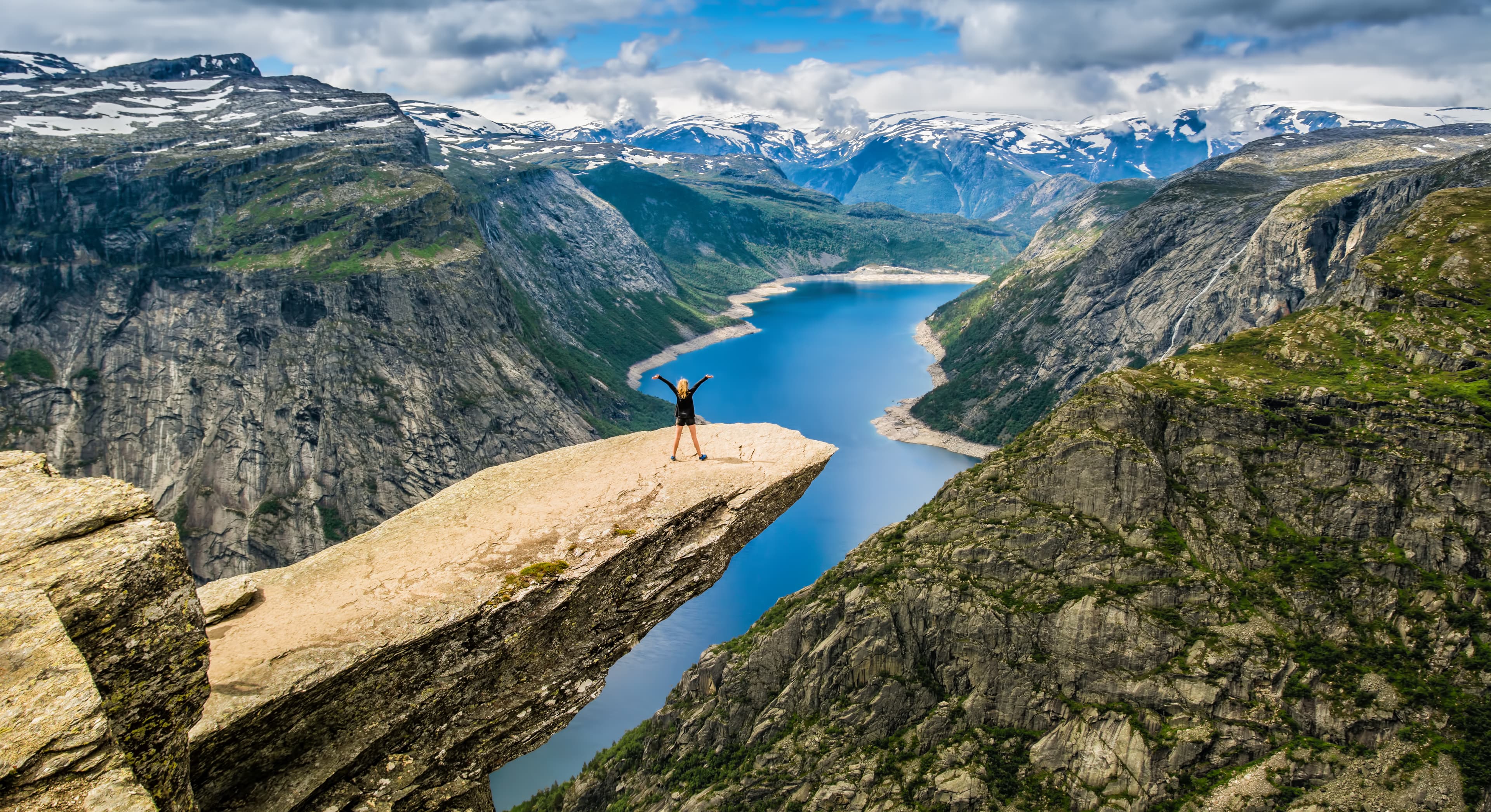 Amazing nature view with Trolltunga and a girl standing  on it. Location: Scandinavian Mountains, Norway, Stavanger. Artistic picture. Beauty world. The feeling of complete freedom Amazing nature view with Trolltunga and a girl standing  on it. Location: Scandinavian Mountains, Norway, Stavanger. Artistic picture. Beauty world. The feeling of complete freedom