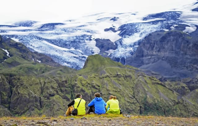 Group of hikers sitting on a ledge of a mountain, enjoying the beautiful view valley in Thorsmork, Iceland Group of hikers sitting on a ledge of a mountain, enjoying the beautiful view valley in Thorsmork, Iceland