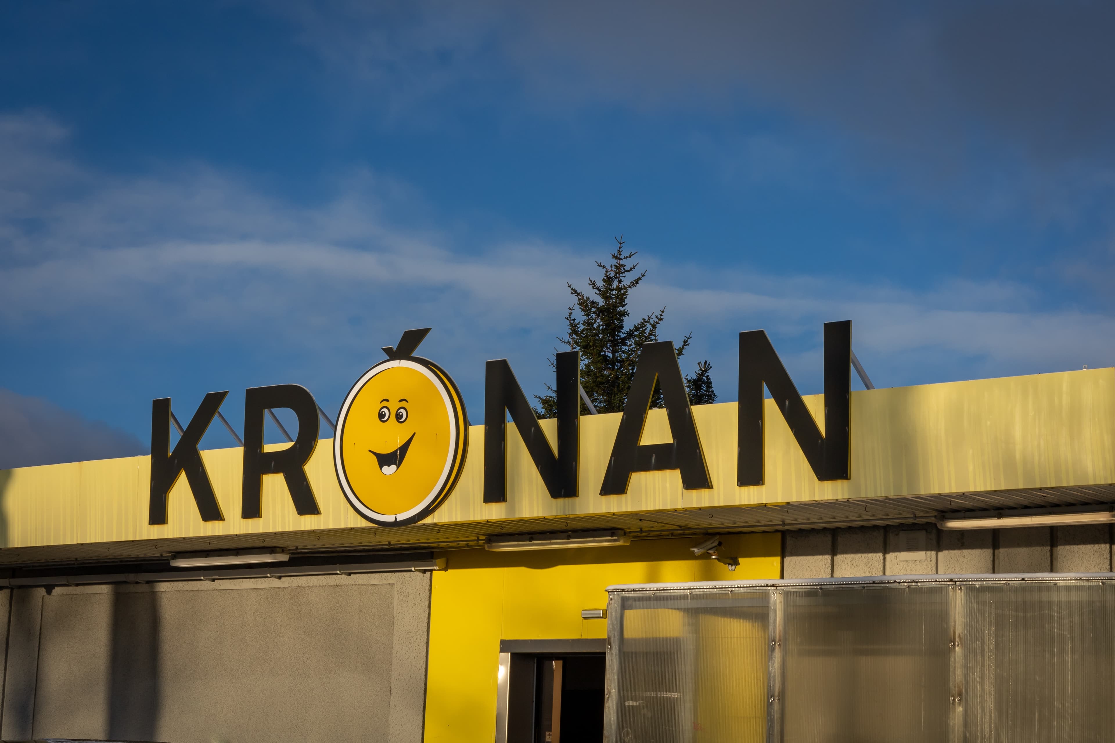 Reykjavik, Iceland - January 25, 2022: Yellow logo of Kronan supermarket. Blue sky with copyspace.