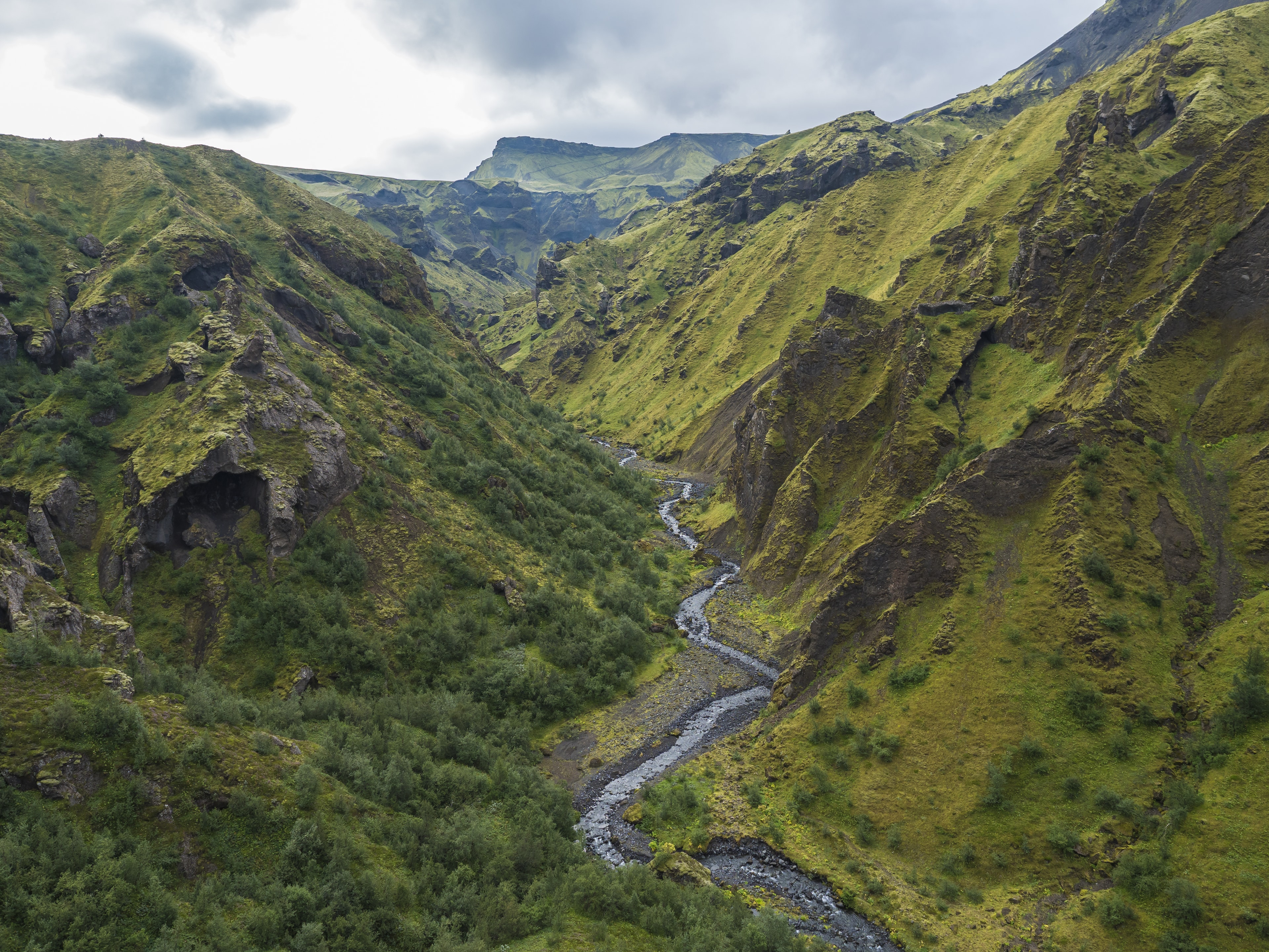 Landscape of Godland and thorsmork with rugged green moss covered rocks and hills, bending river canyon, Iceland, Fimmvorduhals trek. Summer cloudy day. Landscape of Godland and thorsmork with rugged green moss covered rocks and hills, bending river canyon, Iceland, Fimmvorduhals hiking trail. Summer cloudy day.