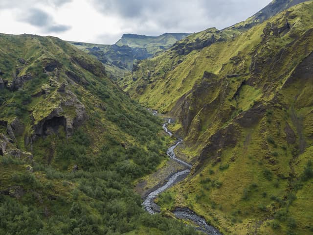 Landscape of Godland and thorsmork with rugged green moss covered rocks and hills, bending river canyon, Iceland, Fimmvorduhals trek. Summer cloudy day. Landscape of Godland and thorsmork with rugged green moss covered rocks and hills, bending river canyon, Iceland, Fimmvorduhals hiking trail. Summer cloudy day.