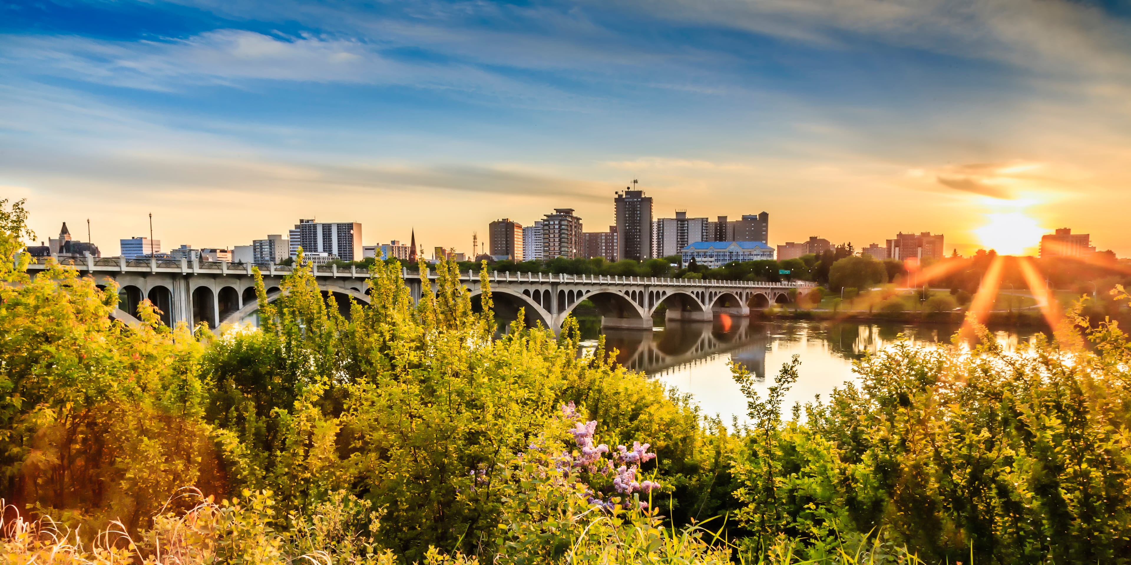 A warm summer sunset over the city of Saskatoon located in Central Canada where the calm waters of the South Saskatchewan River flows under the University Bridge. Saskatoon City Attraction 5