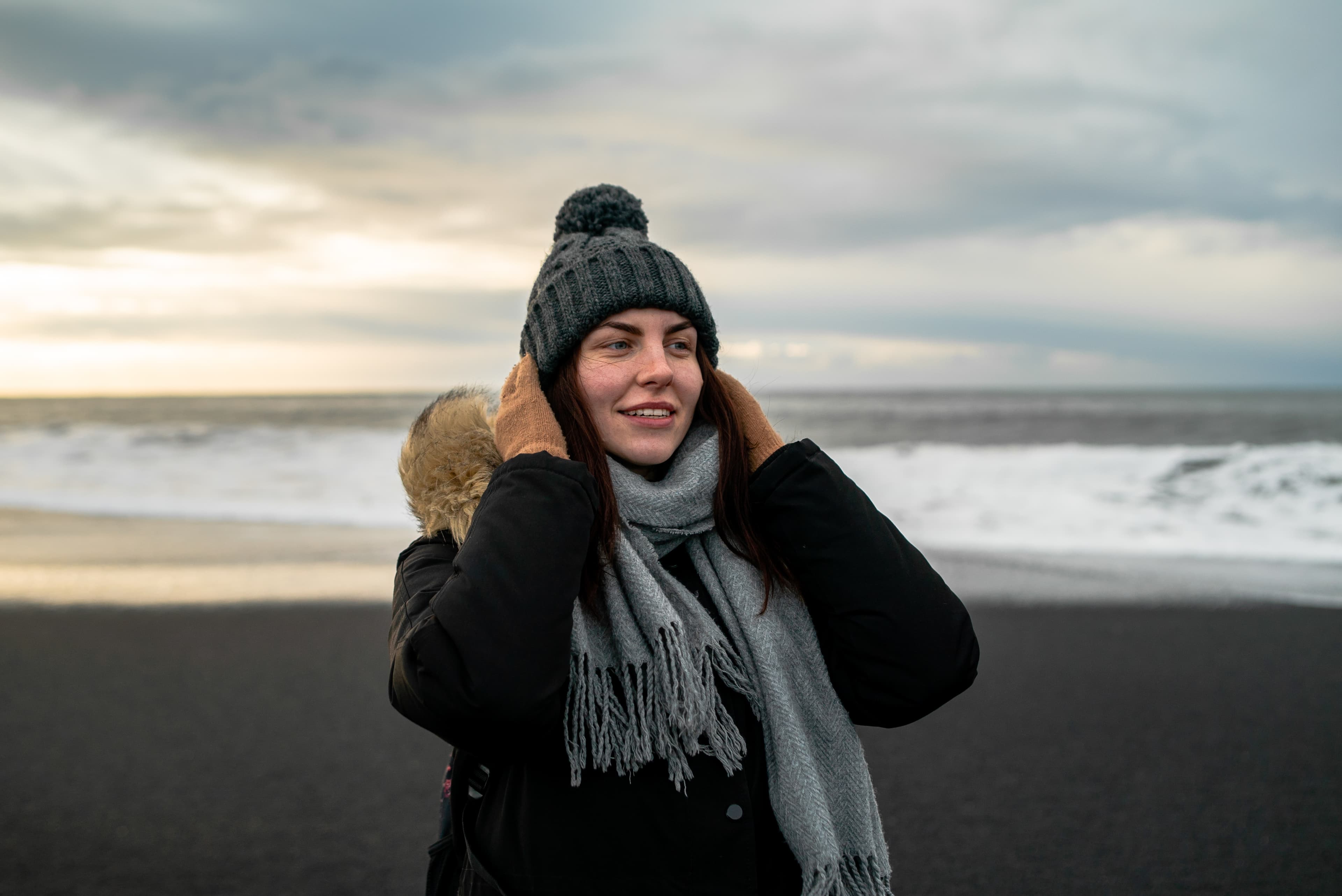 young woman walks on black beach in Iceland