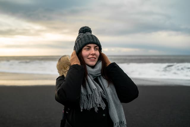 young woman walks on black beach in Iceland