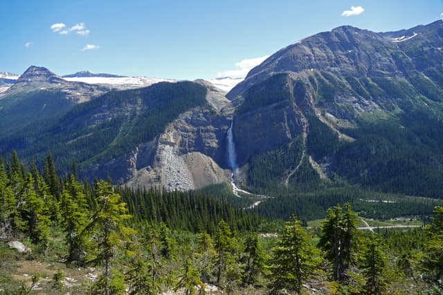 Magnificent Takakkaw Falls in Yoho National Park landscape with rugged mountains, spruce trees and blue sky, summer tourist hiking destination, Canadian Rockies, British Columbia, Canada Magnificent Takakkaw Falls in Yoho National Park landscape with rugged mountains, spruce trees and blue sky, summer tourist hiking destination, Canadian Rockies, British Columbia, Canada