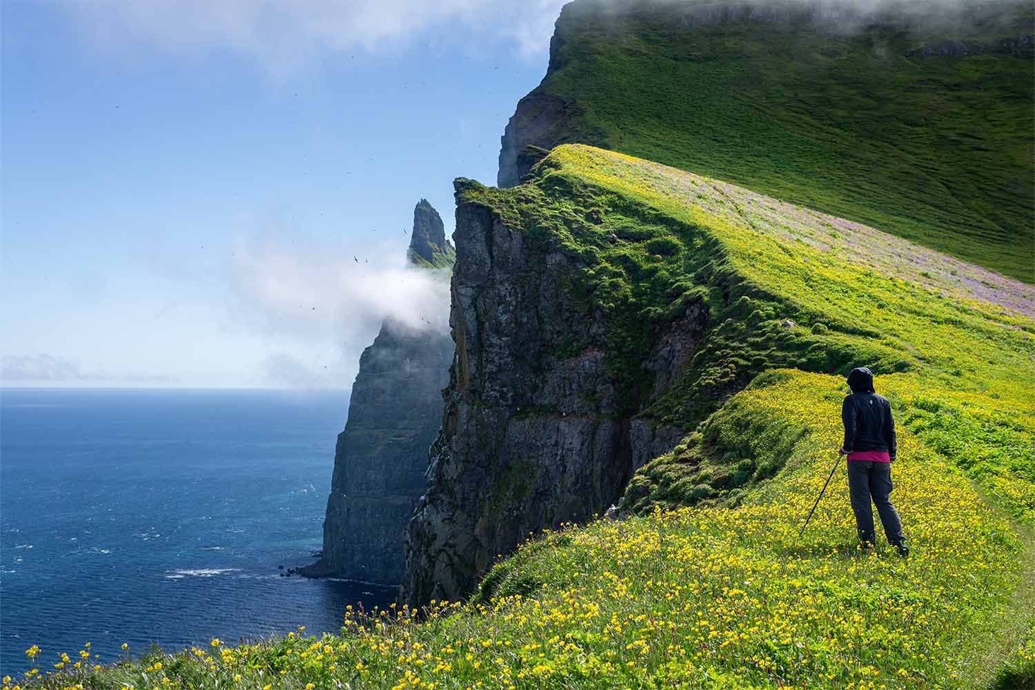 Woman-standing-and-watching-the-ocean-from-cliffs-of-Westman-Islands