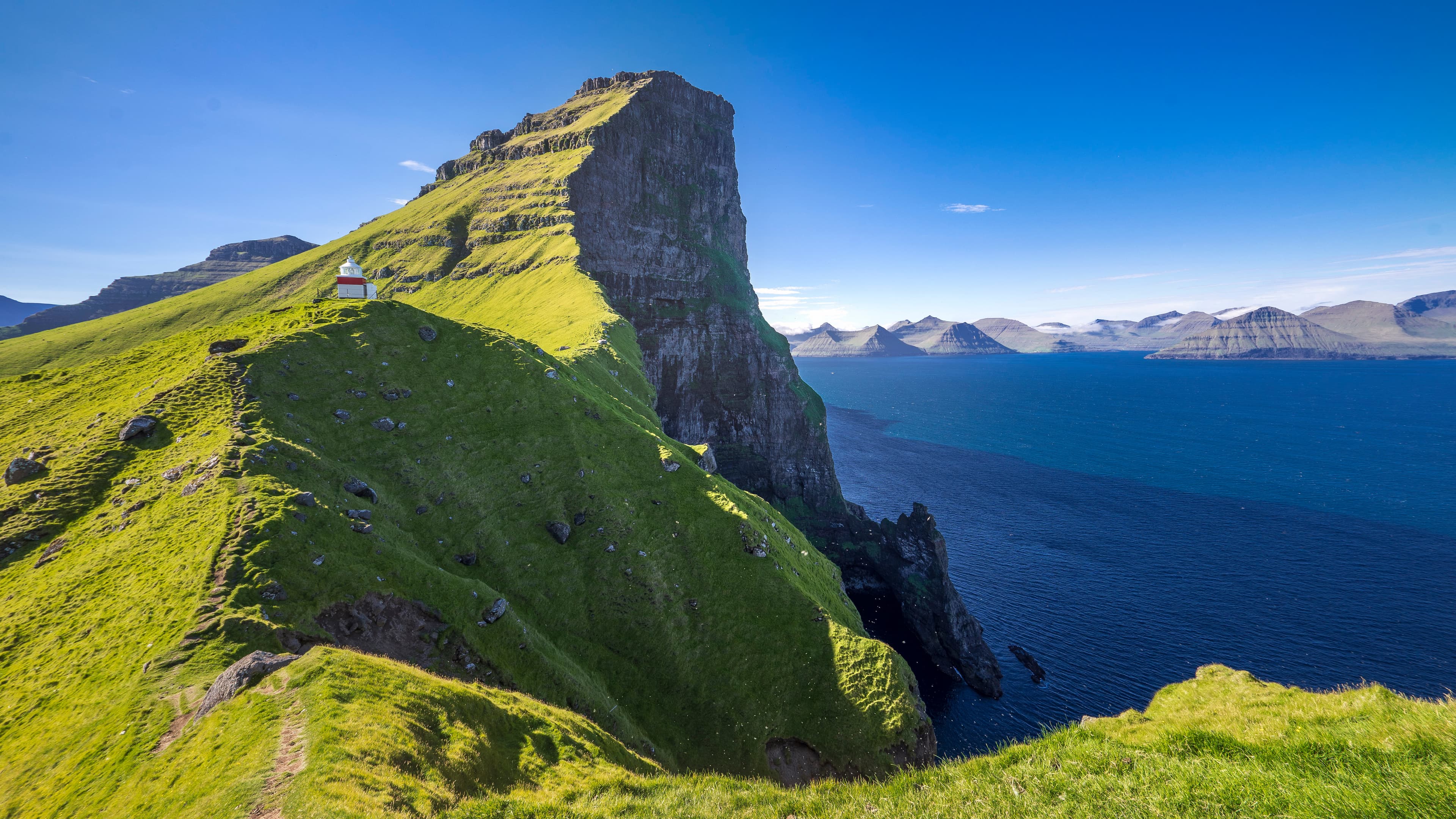 Der Lechtturm Kallur auf der Färör Insel Kalsoy steht einsam auf einer Landzuge über dem Meer und ist ein lohnenswertes Ziel für Wanderer. Das Panorama von den steilen Klippen ist beeindruckend.