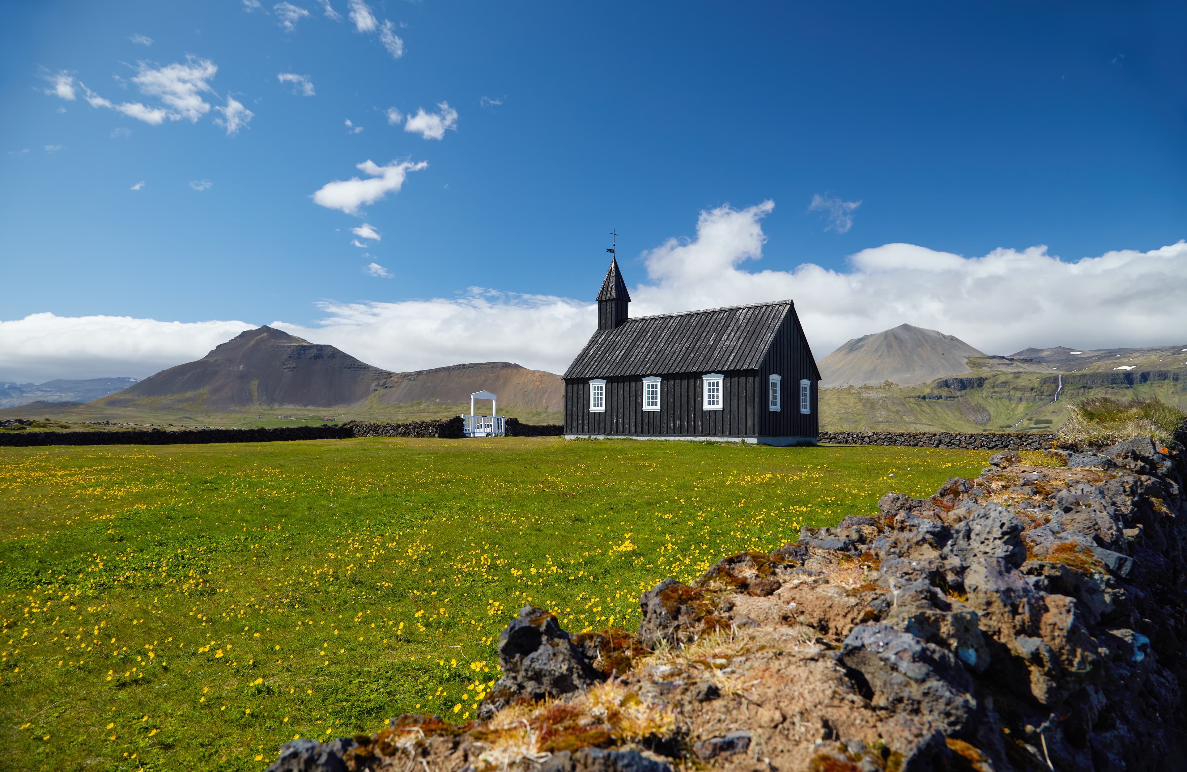 Black wooden church Budakirkja at Snaefellsnes peninsula, Budir village, Western Iceland, Europe. Summer landscape with chapel, mountains and flowers. Famous landmark. Travelling concept background. Black wooden church Budakirkja at Snaefellsnes peninsula, Budir village, Western Iceland, Europe. Summer landscape with chapel, mountains and flowers. Famous landmark. Travelling concept background.