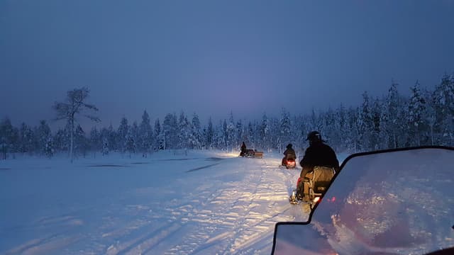 Snowmobile safari during the midnight sun in finnish Lapland. Snowmobiling in Rovaniemi behind the Arctic circle. Finland.