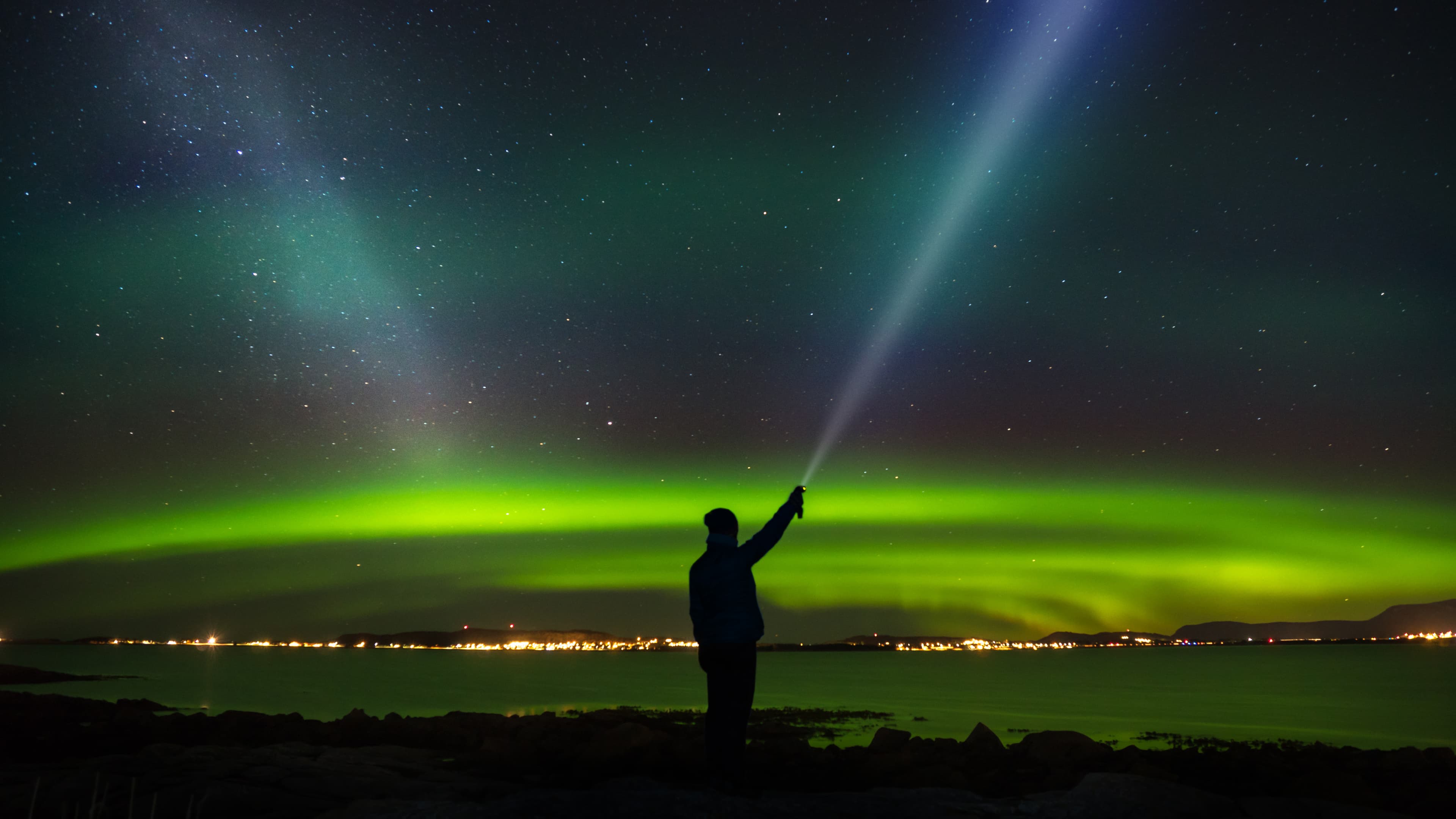 Woman standing with headlamp in the tide looking at nightsky, milky way and aurora. Woman standing with headlamp in the tide looking at nightsky, milky way and aurora.