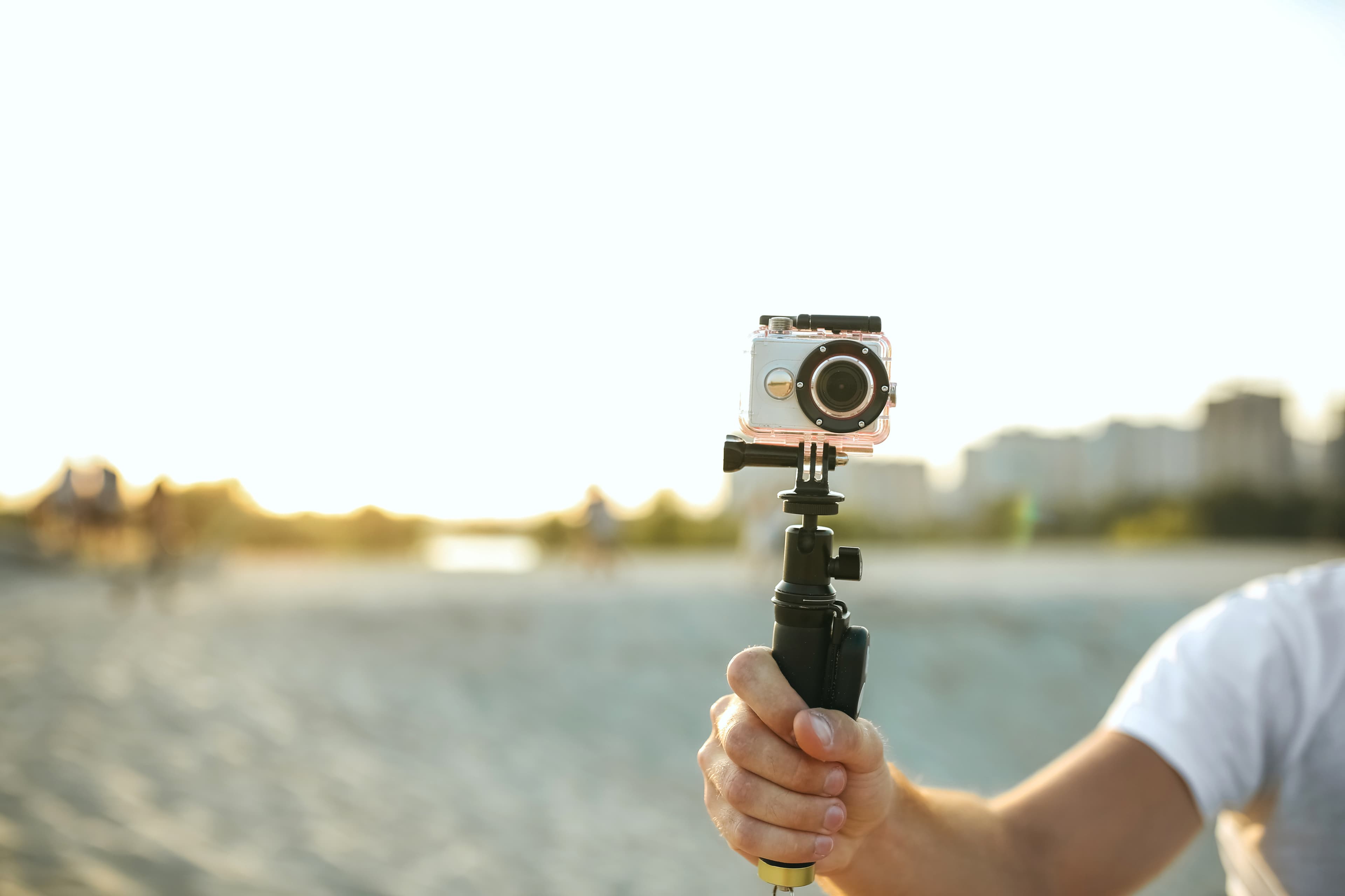Young man holding an action camera at the desert. Space for text Young man holding an action camera at the desert. Empty space
