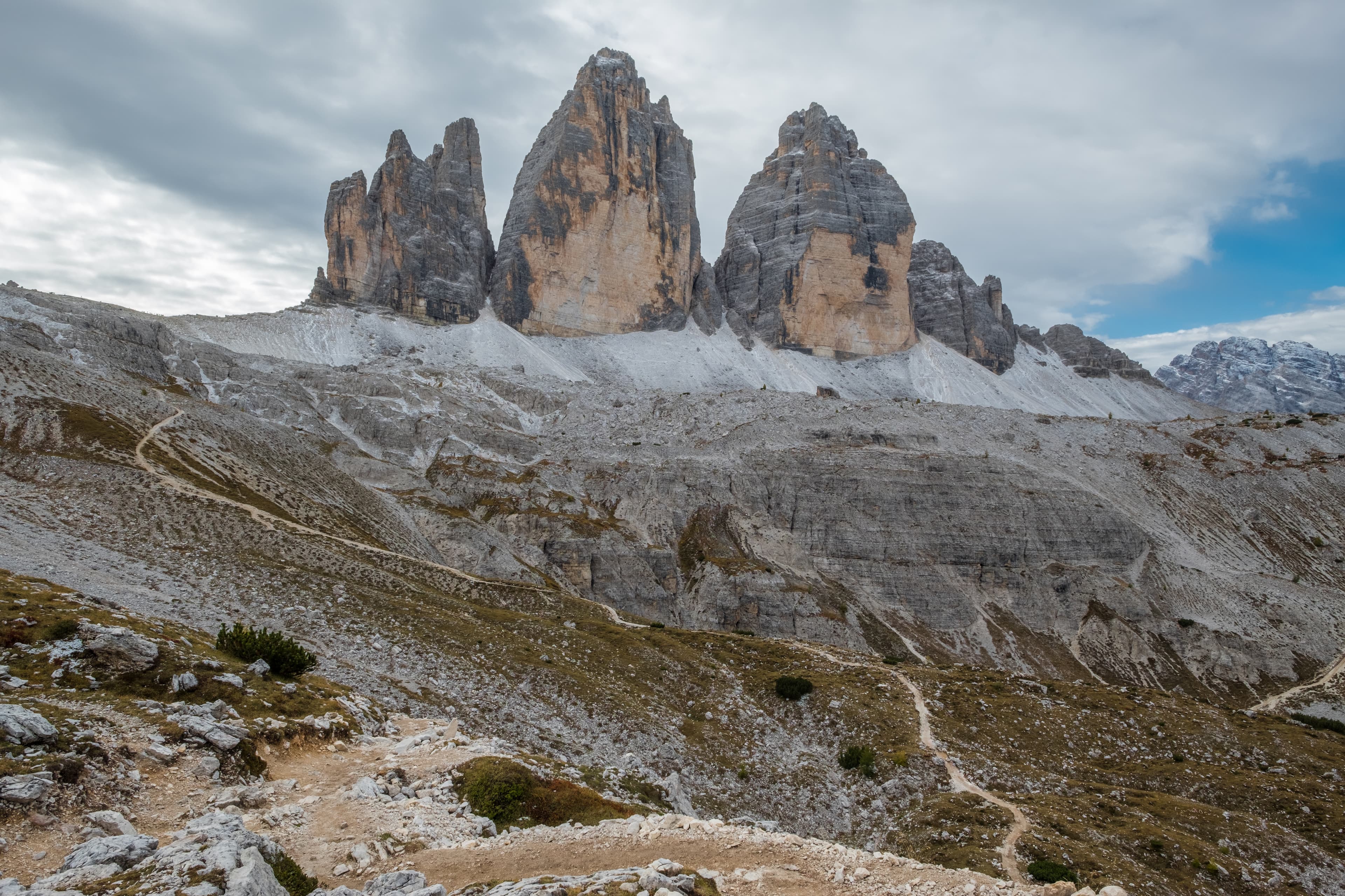 A walking path zig-zags up a rocky slope towards the striking rock formations known as the Three Chimneys or Tre Cime in Italy or Drei Zinnen in Austria. Tre Cime - Drei Zinnen - Three Chimneys.  Dolomites, Italy