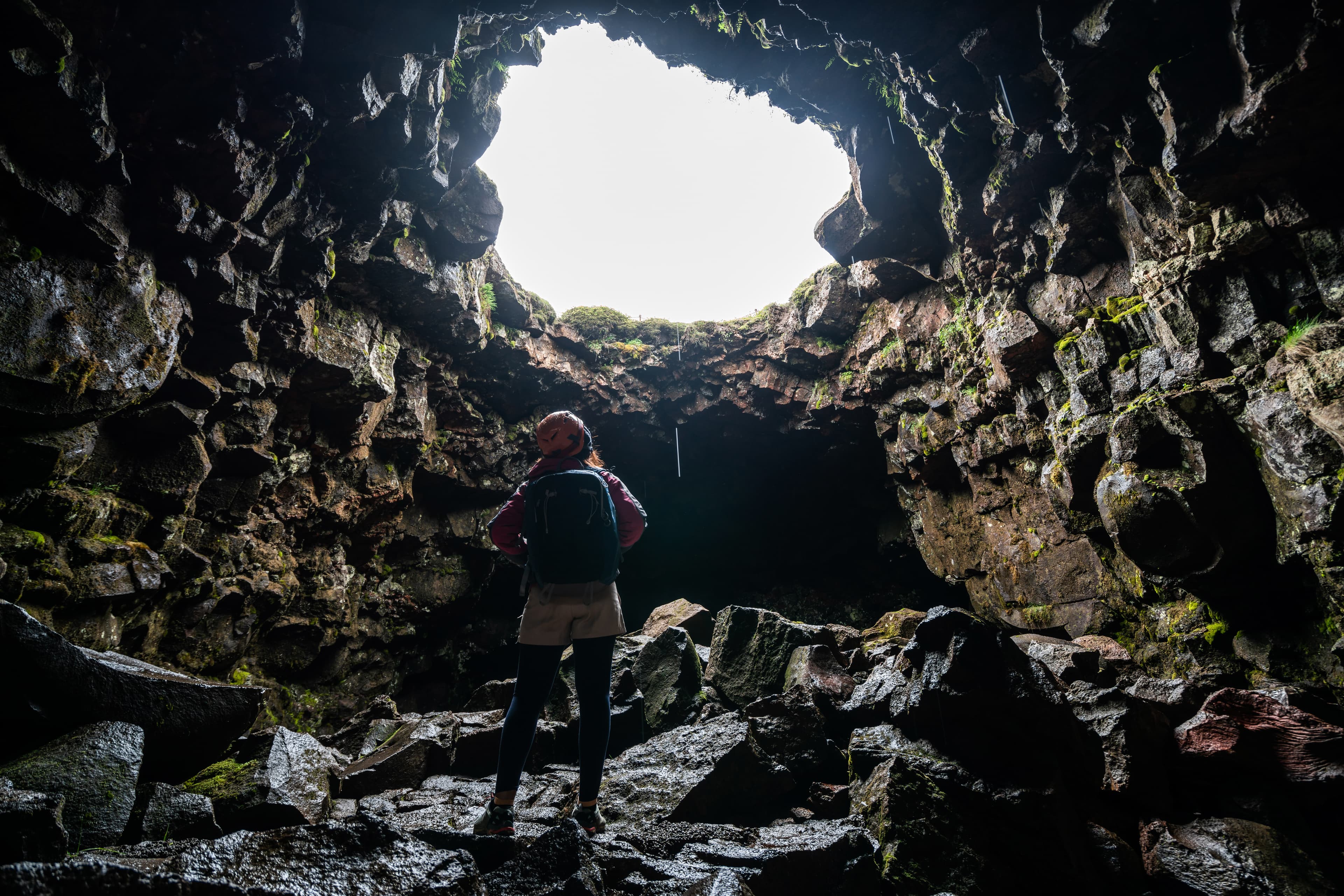 Woman traveler explore lava tunnel in Iceland. Raufarholshellir is a beautiful hidden world of cave. It is one of the longest and best-known lava tubes in Iceland, Europe for incredible adventure. Raufarholshellir-woman-lava-tunnel-cave