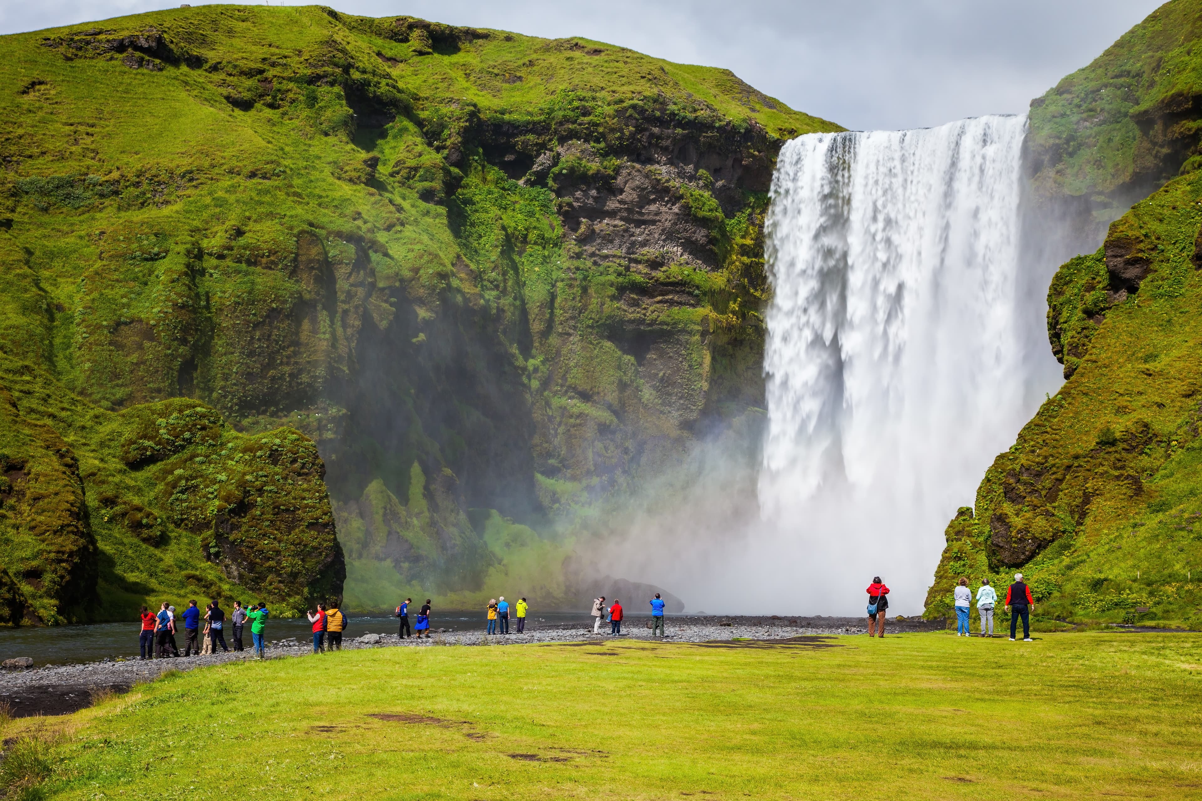 Magnificent famous waterfall Skógafoss, Iceland. A powerful jet Skógar river falls from a large glacier. Tourists delighted the crowd at the foot of roaring jets Magnificent  waterfall Skógafoss, Iceland