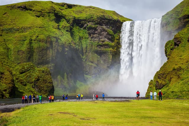 Magnificent famous waterfall Skógafoss, Iceland. A powerful jet Skógar river falls from a large glacier. Tourists delighted the crowd at the foot of roaring jets Magnificent  waterfall Skógafoss, Iceland