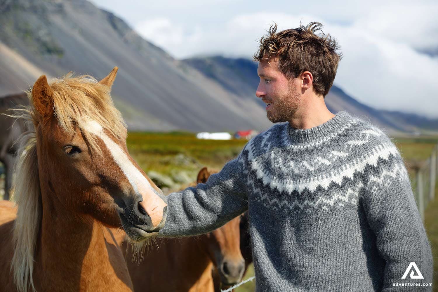 a-man-in-icelandic-wool-sweater-petting-a-horse-on-a-riding-tour-in-iceland