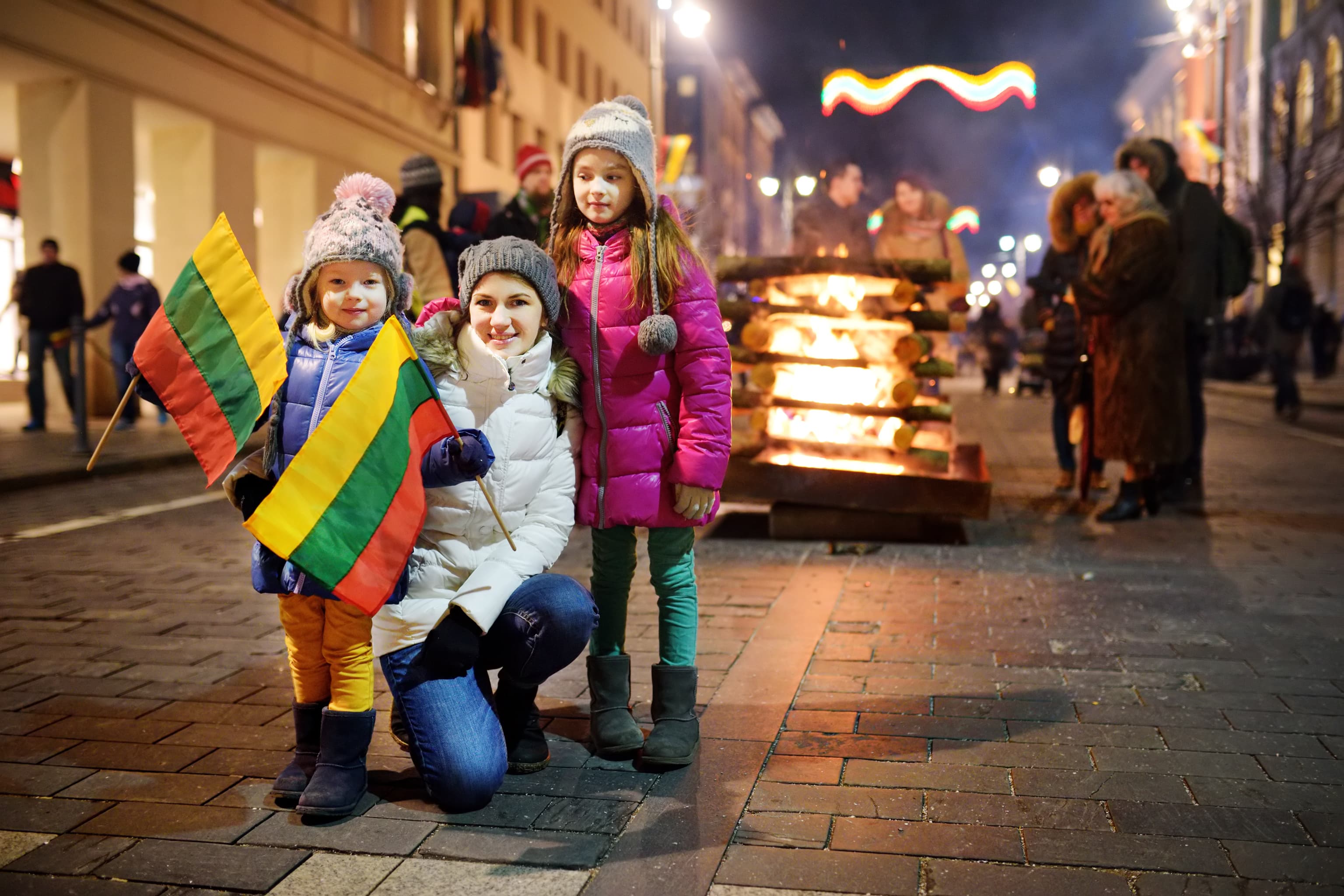 Happy family with kids attending the celebration of Restoration of the State Day in Vilnius, Lithuania. Bonfires are lit on Gediminas avenue on the night on February 16. Family with kids attending the celebration of Restoration of the State Day in Vilnius, Lithuania. Bonfires are lit on Gediminas avenue on the night on February 16.