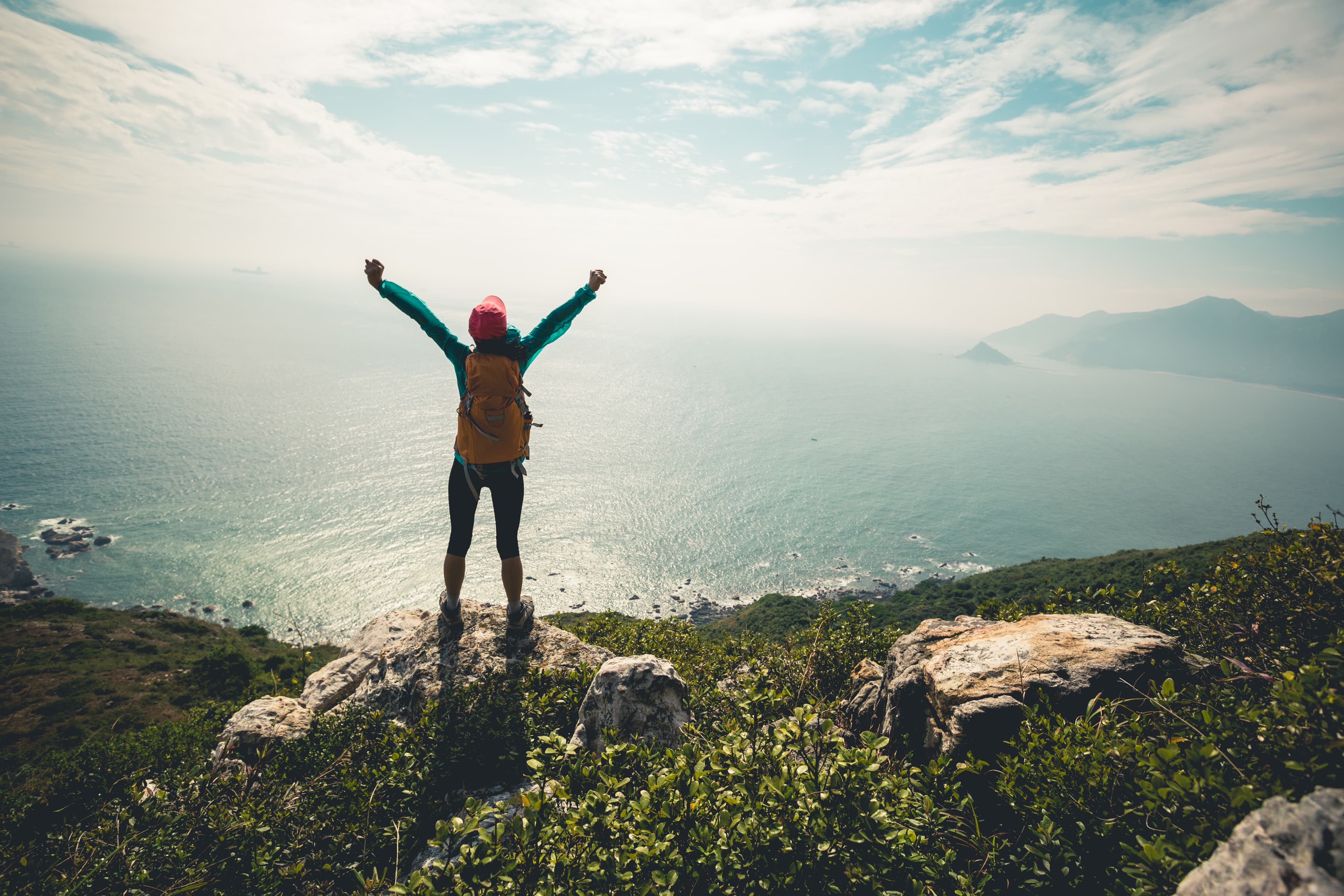 Successful hiker outstretched arms at seaside mountain top cliff edge Successful hiker outstretched arms at seaside mountain top cliff edge