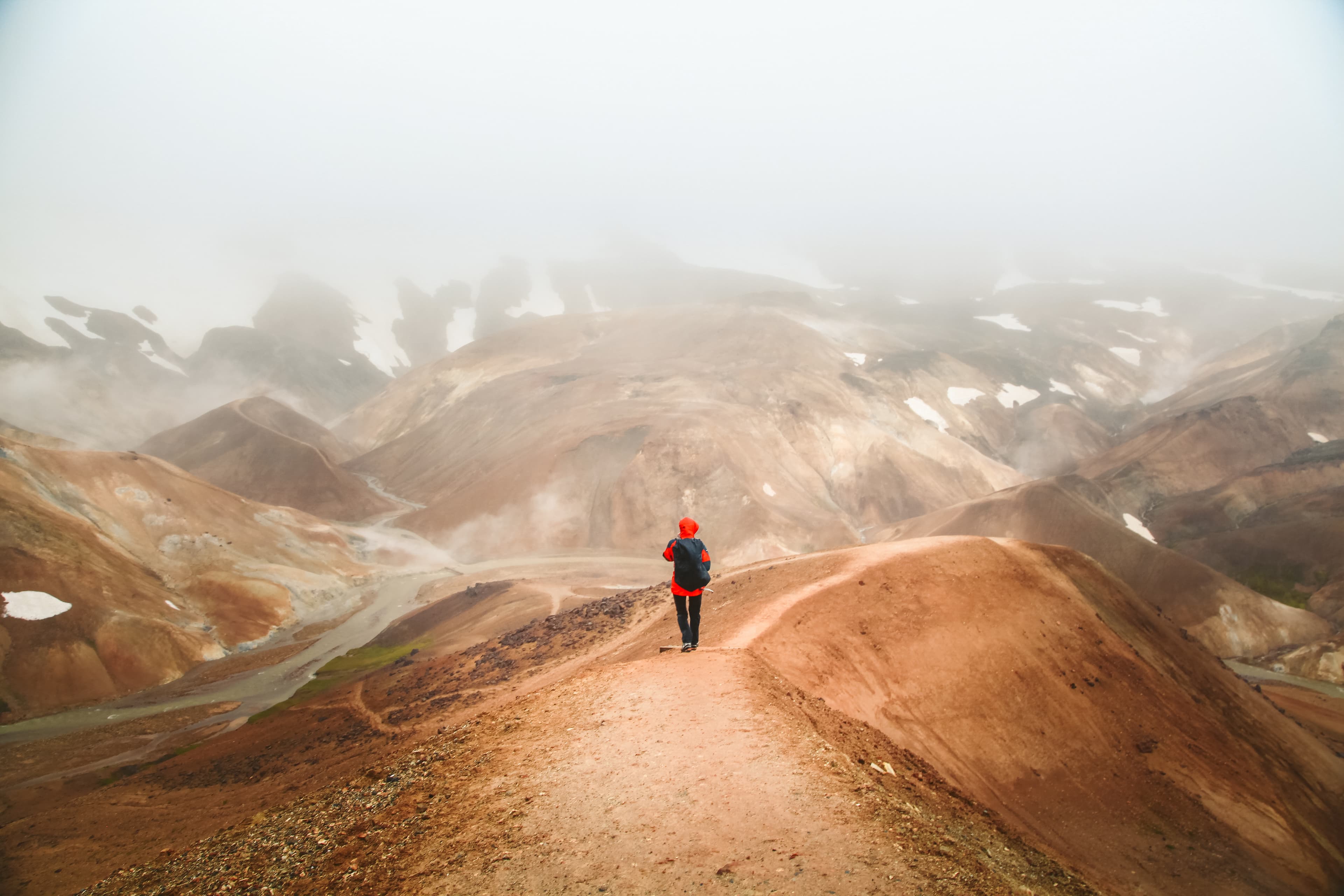 Beautiful view of idyllic geothermal mountain scenery with person hiking in Landmannalaugar in the highlands of Iceland Hiker in Landmannalaugar highlands, Iceland