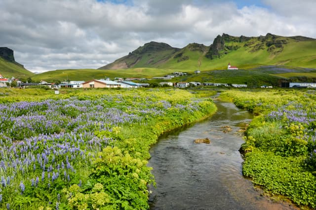 Landscape of Vik village and river, Iceland with Myrdal Church in background on summer day with dramatic sky Landscape of Vik village and river, Iceland with Myrdal Church in background on summer day with dramatic sky