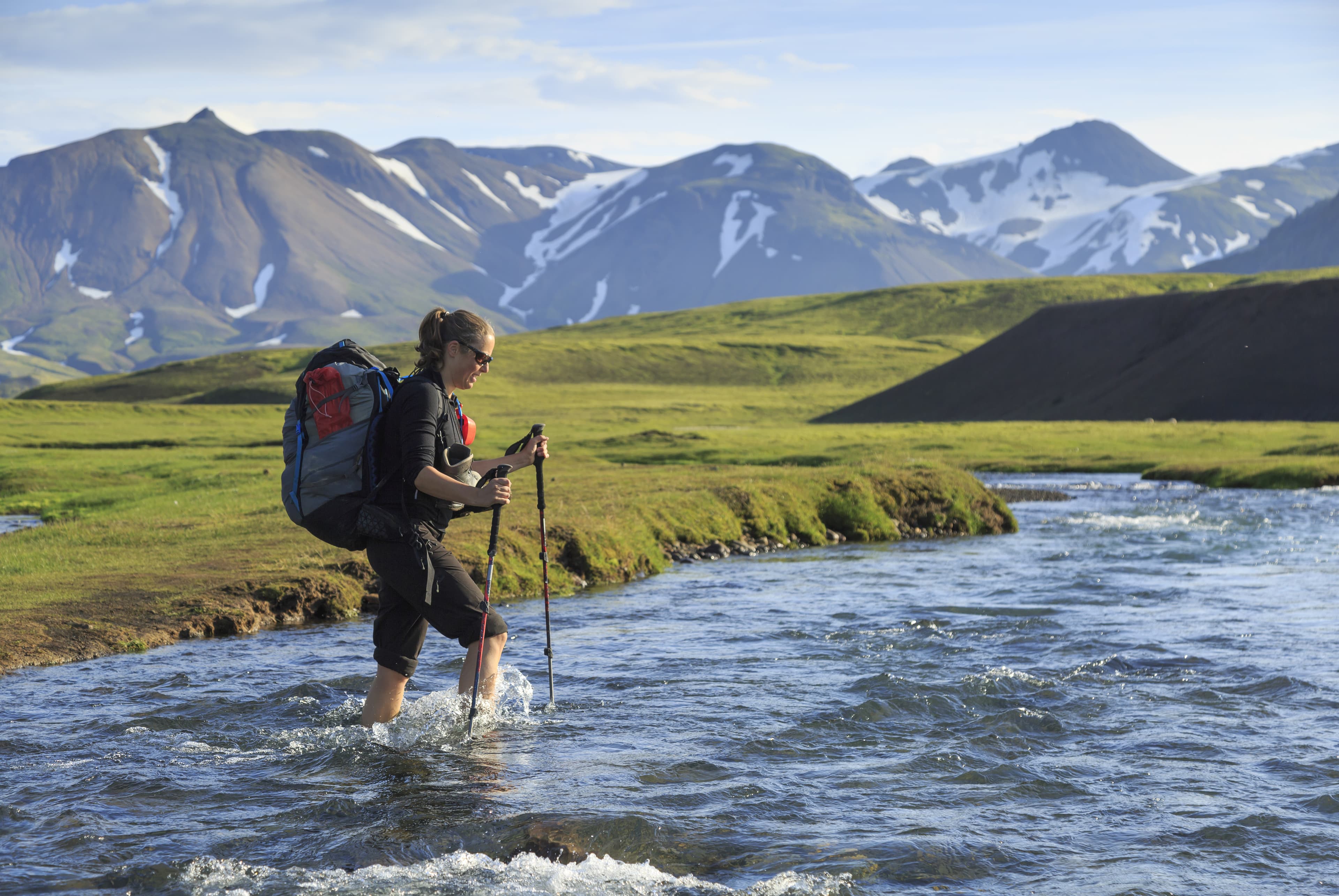 Female hiker crossing a river on the Laugavegur trail on Iceland. Female hiker crossing a river on the Laugavegur trail on Iceland.