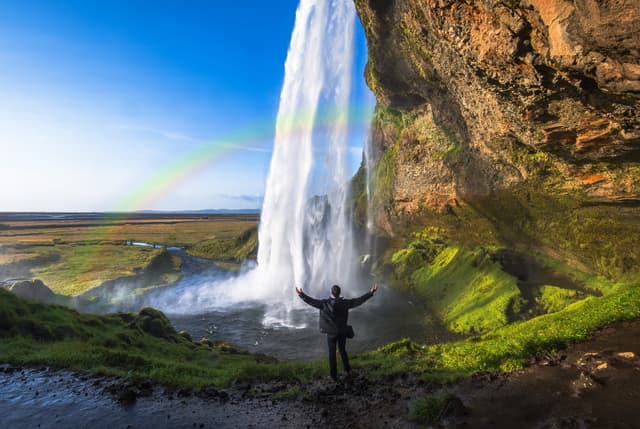 Tourist standing in front of Seljalandsfoss one of the best known waterfalls in southern Iceland, The most famoust Icelandic waterfall , beautiful amazing landscape from Iceland, Tourist standing in front of Seljalandsfoss one of the best known waterfalls in southern Iceland, Seljalandsfoss , Iceland