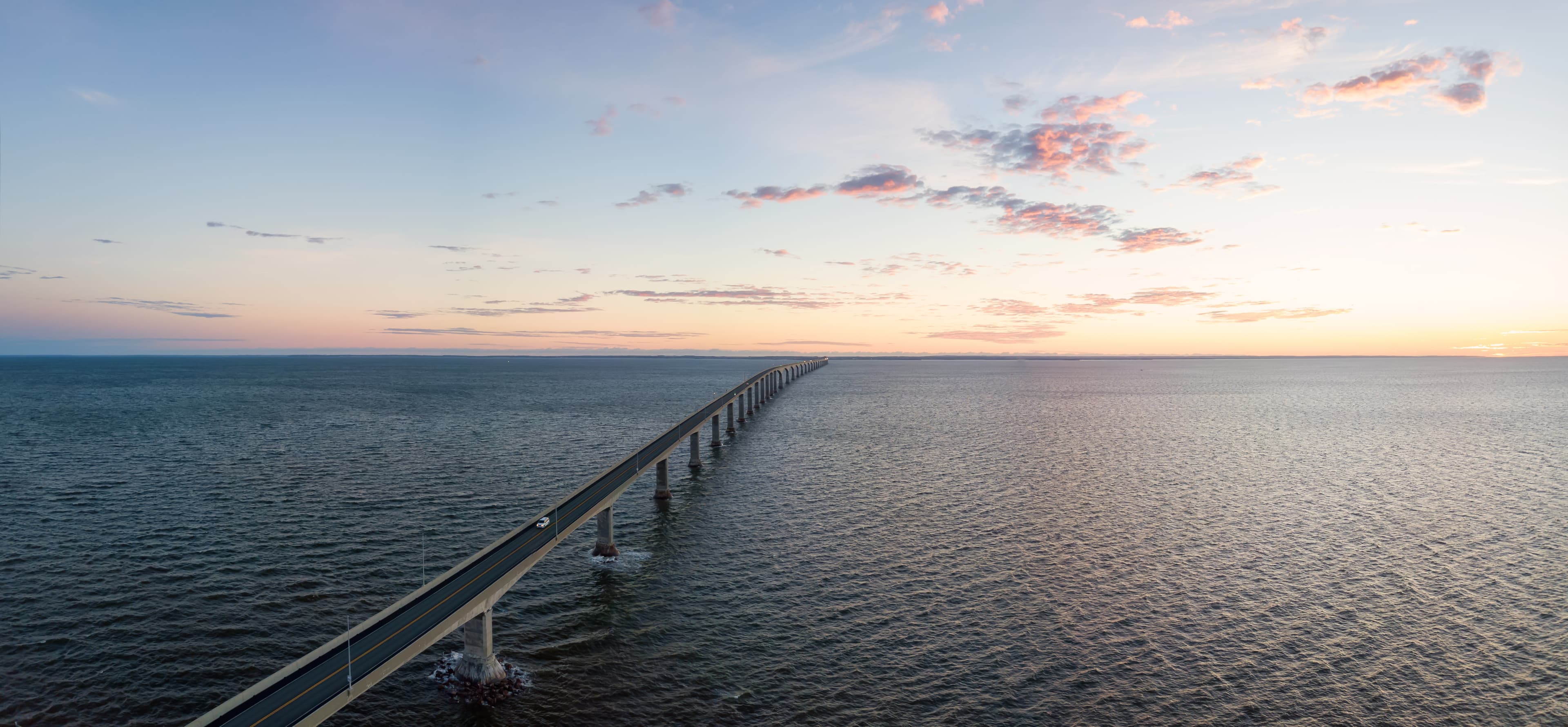 Aerial Panoramic view of Confederation Bridge to Prince Edward Island during a vibrant sunny sunrise. Taken in Cape Jourimain National Wildlife Area, New Brunswick, Canada. Aerial Panoramic view of Confederation Bridge to Prince Edward Island during a vibrant sunny sunrise. Taken in Cape Jourimain National Wildlife Area, New Brunswick, Canada.