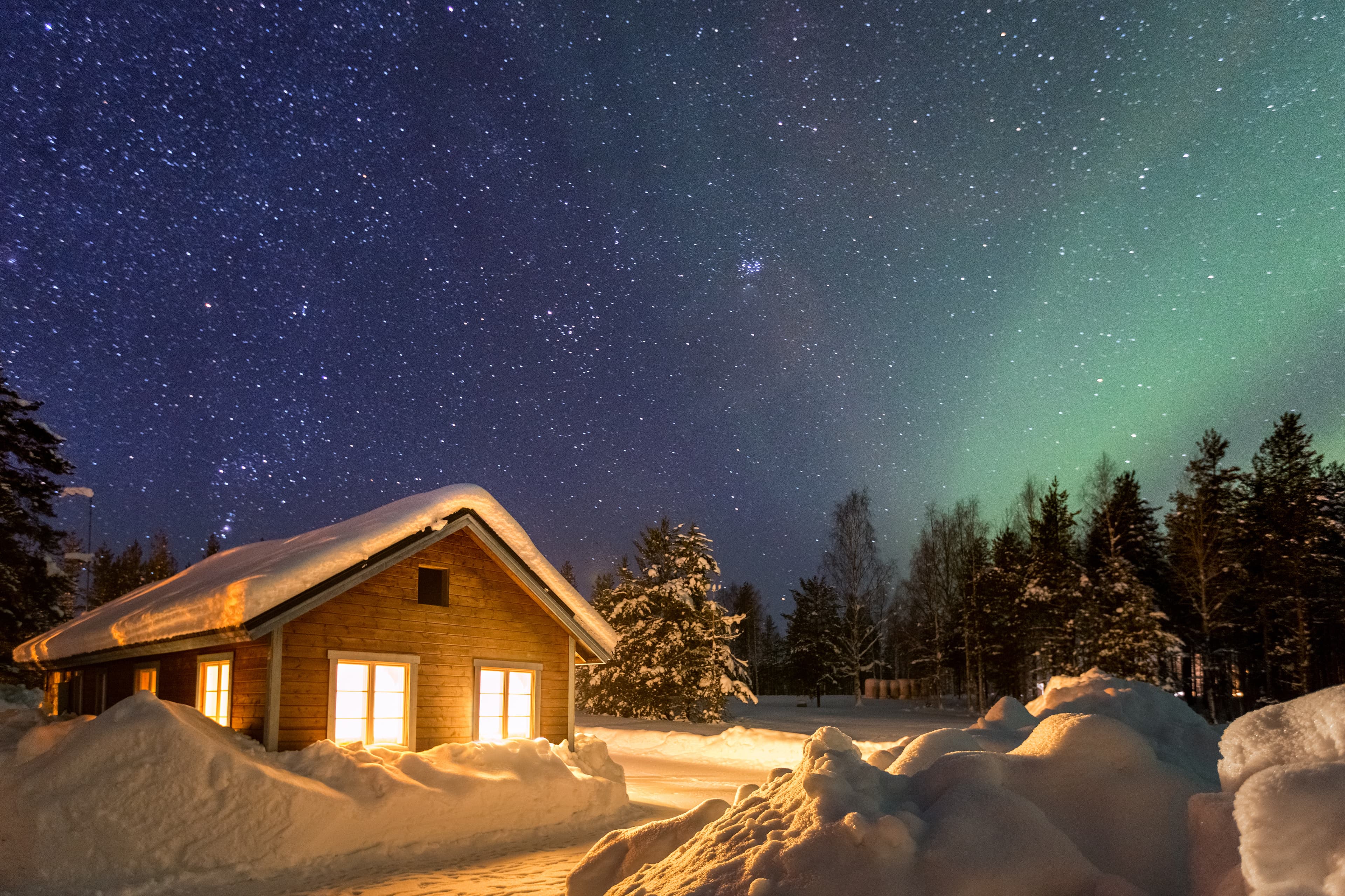 Winter landscape with wooden house under a beautiful starry sky and Northern Lights, Sweden Winter landscape with wooden house under a beautiful starry sky and Northern Lights