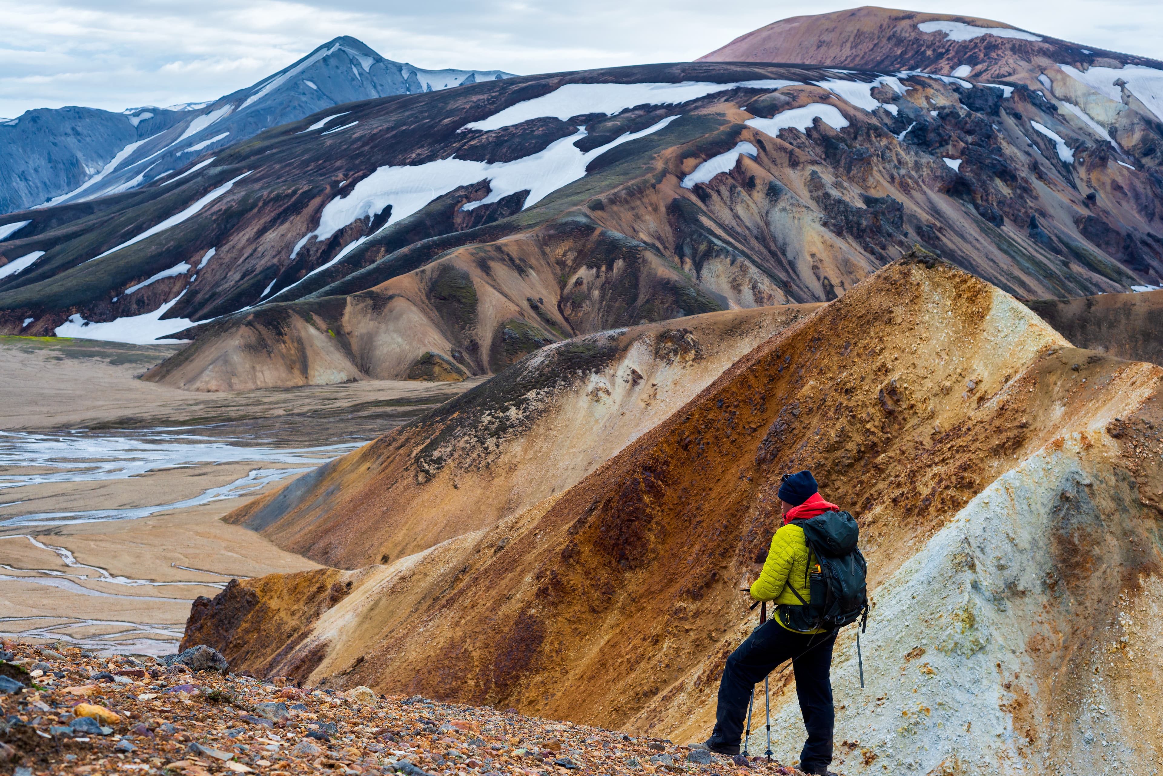 Man hiker looking at the colorful mountain in Landmannalaugar, Iceland Man hiker looking at the colorful mountain in Landmannalaugar, Iceland