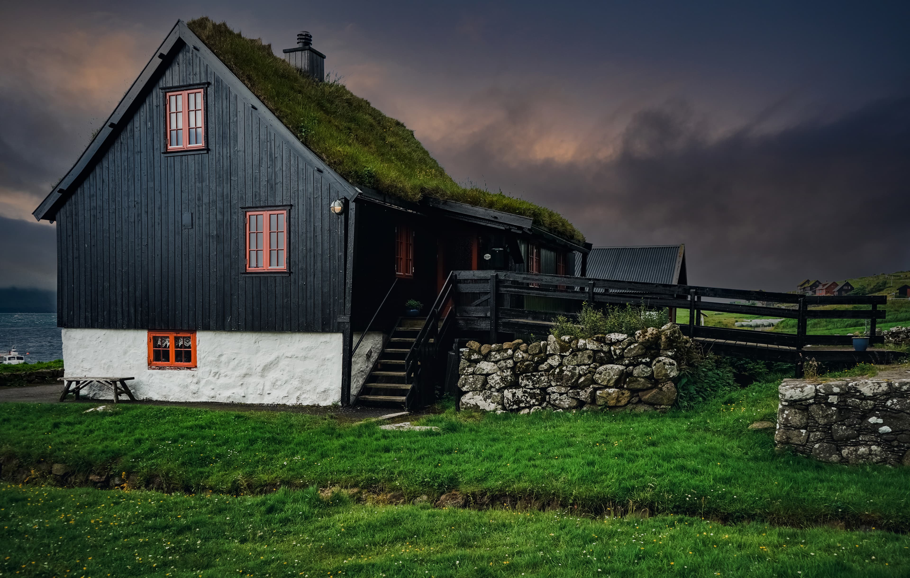 Nice cloudy sunset on Traditional turf house in Village of Kirkjubour. Typical black house in Faroe Islands, Denmark, Northern Europe. Nice cloudy sunset on Traditional turf house in Village of Kirkjubour. Typical black house in Faroe Islands, Denmark, Northern Europe.