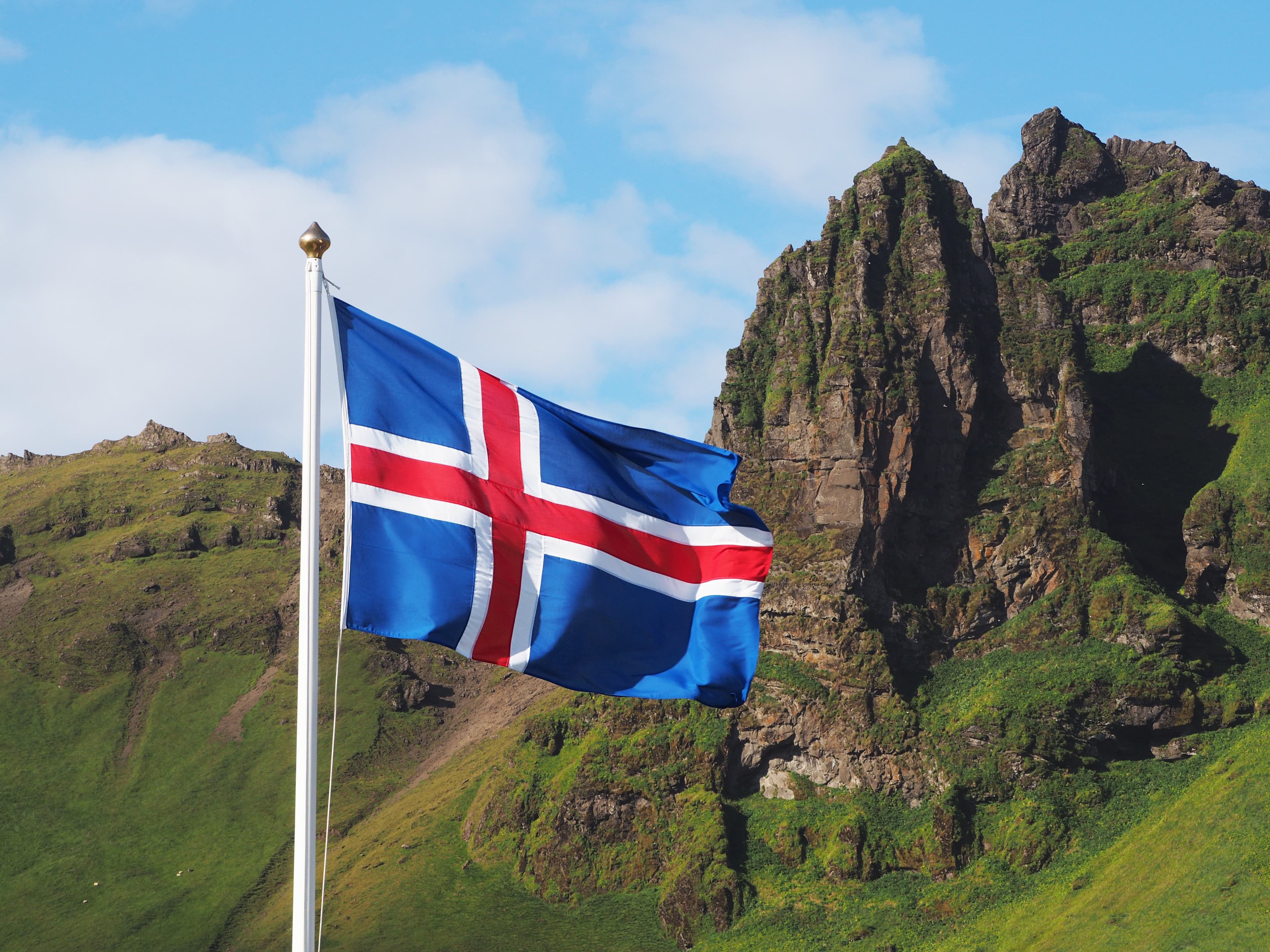 OLYMPUS DIGITAL CAMERA Flag of Iceland against the background of green mountains and blue sky