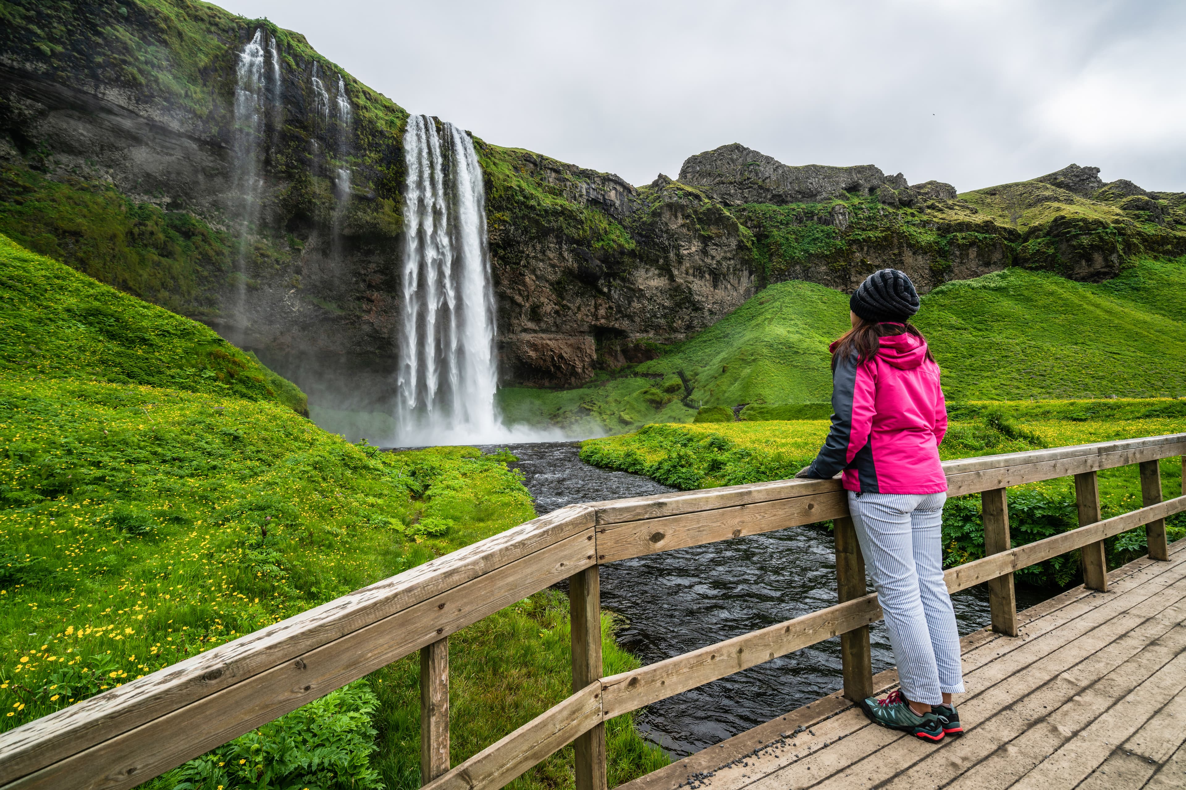 Woman traveler at Magical Seljalandsfoss Waterfall in Iceland located near ring road of South Iceland. Majestic and picturesque, it is one of most photographed breathtaking place of Iceland wilderness Woman traveler at Magical Seljalandsfoss Waterfall in Iceland located near ring road of South Iceland. Majestic and picturesque, it is one of most photographed breathtaking place of Iceland wilderness