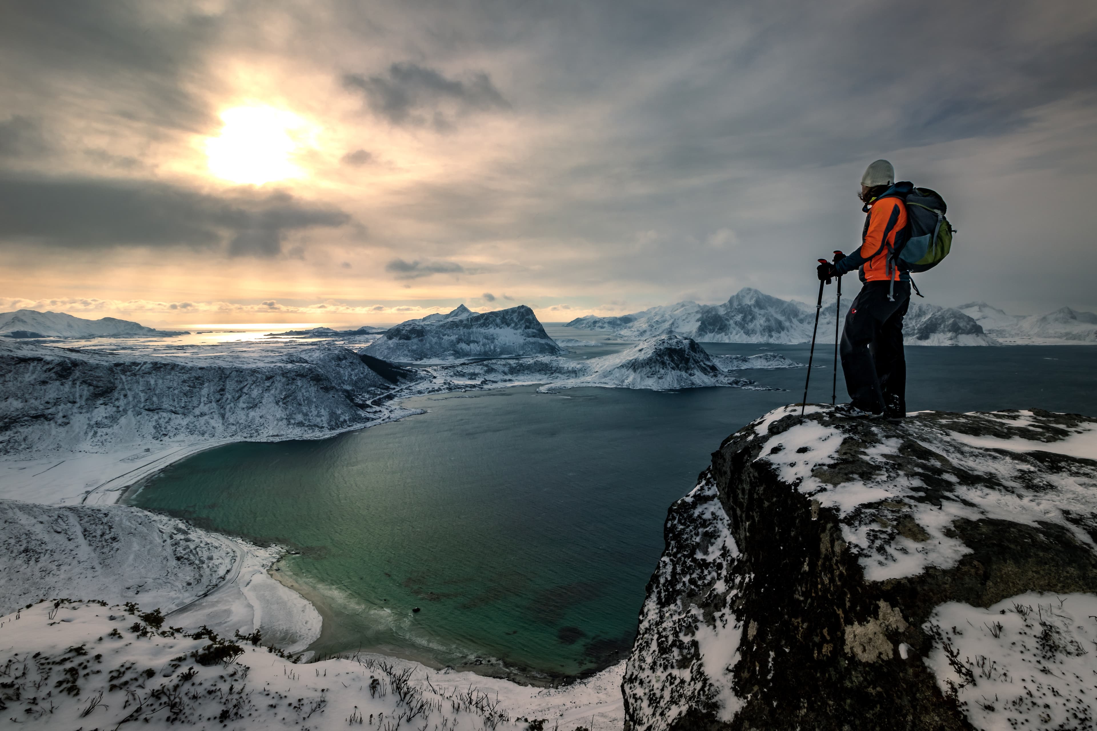 Winter Hiker on the slope of Mannen Mountain looking down to Haukland Beach on the Lofoten Islands in Norway