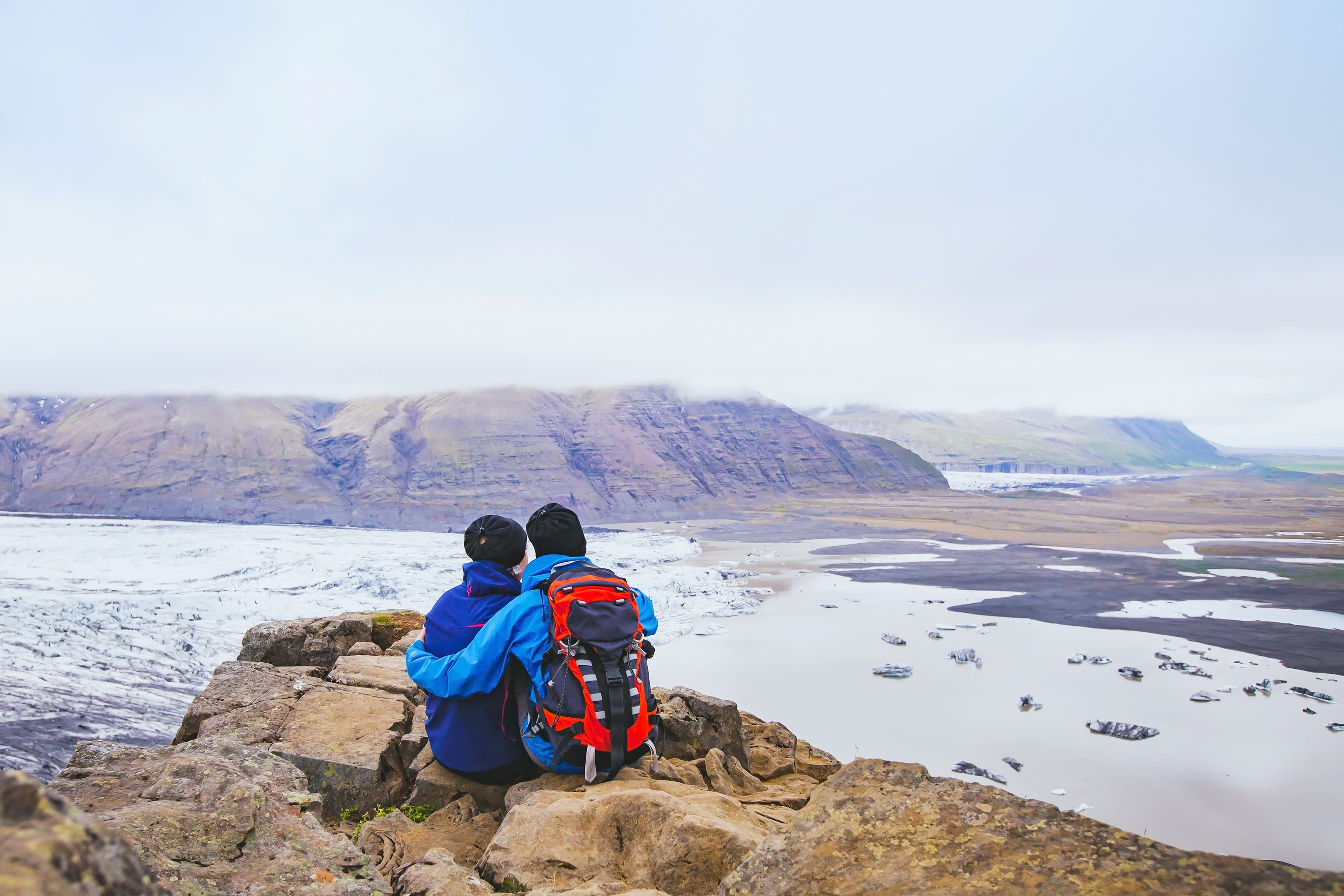 couple of hikers travel in Iceland, two backpackers enjoying view of glacier and mountain landscape couple of hikers travel in Iceland, two backpackers enjoying view of glacier and mountain landscape