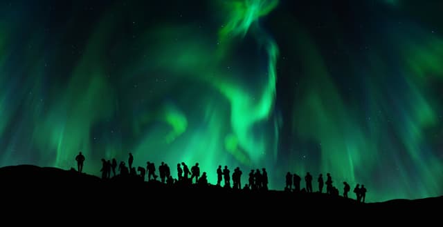 The silhouettes of people under the green northern lights Silhouettes of people under the green northern lights