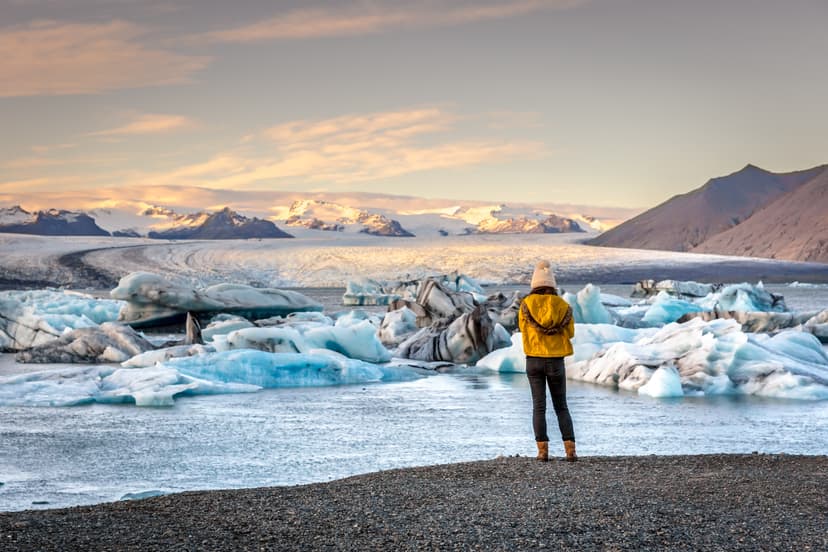 Young woman dressing cold clothes seeing the amazing Jokulsarlon, iceberg lagoon in Iceland Woman-near-Jokulsarlon-glacier-lagoon