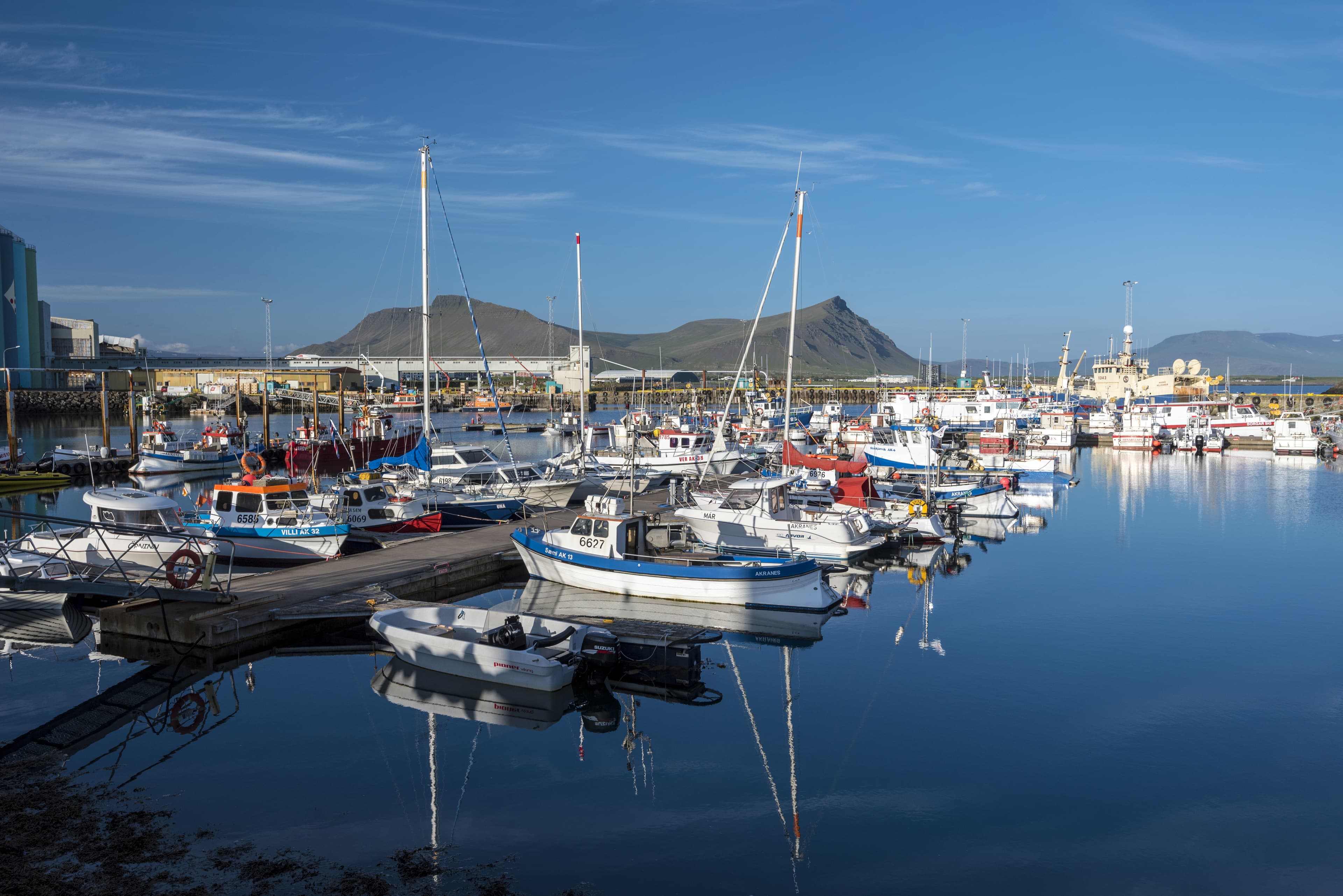Akranes, Iceland – 19 July, 2018. Marine port for fishing boats and private yachts in Akranes town in western coast of Iceland.  Akrafjall mountain massif is at background. Marine port for fishing boats and private yachts in Akranes town in western coast of Iceland.  Akrafjall mountain massif is at background.