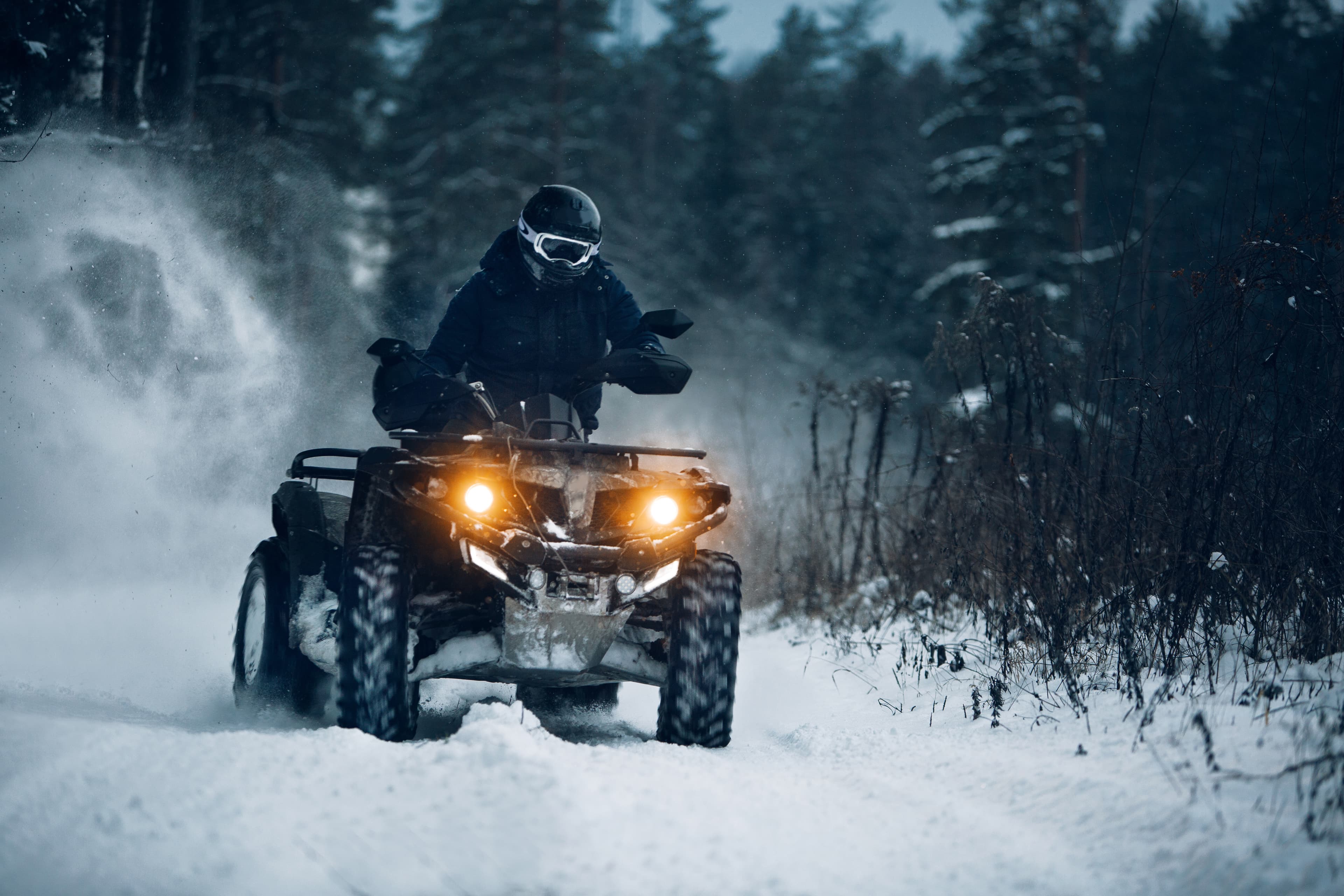 Rider driving in the quadbike in winter in the forest