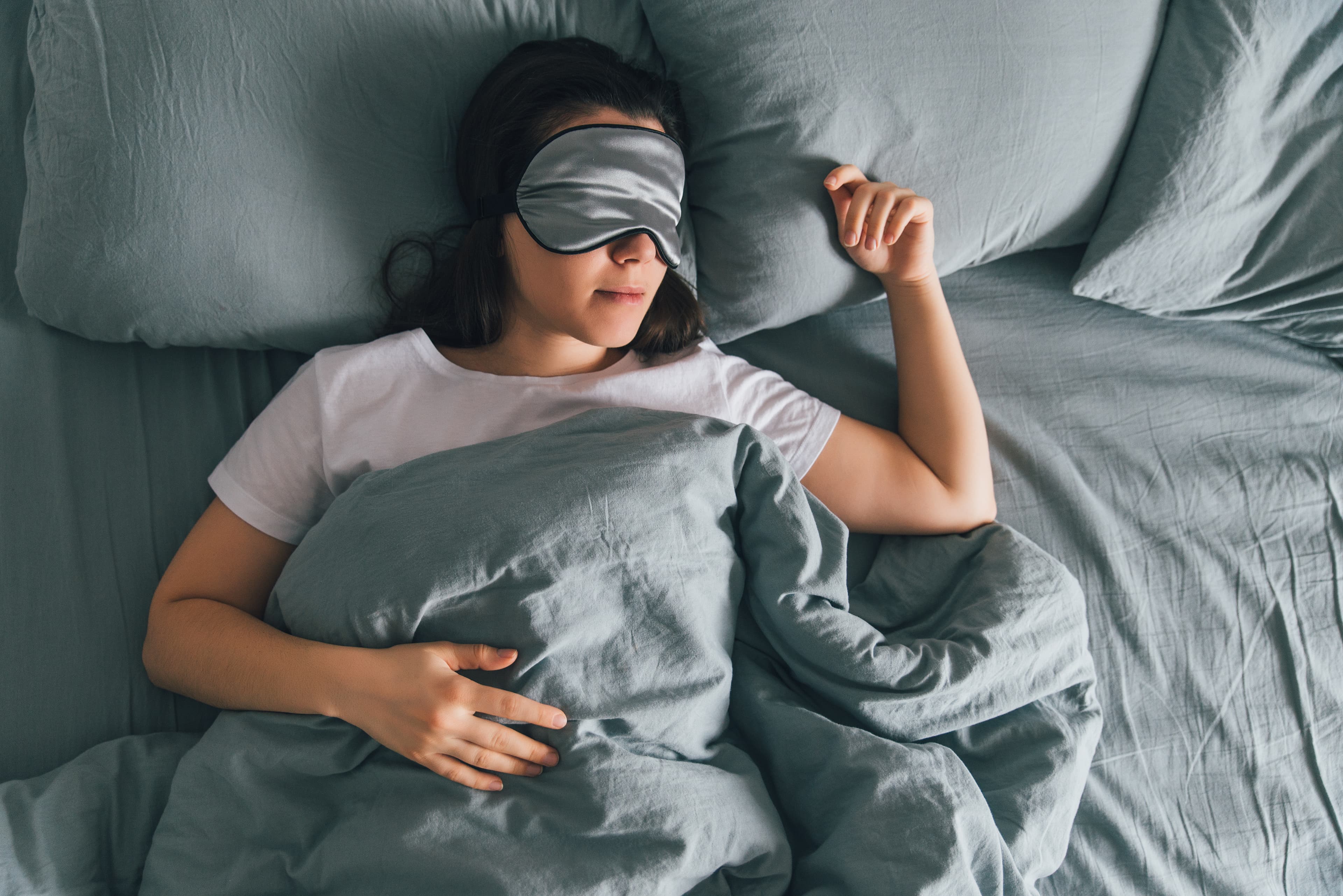 woman sleep in eye patch in grey bed. copy space woman sleep in eye patch in grey bed. copy space