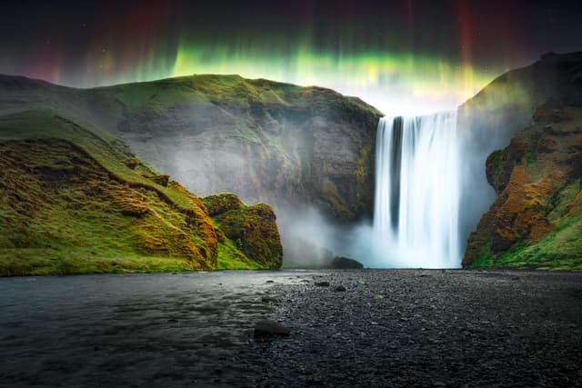 Green aurora light behind famous Skogafoss waterfall on Skoga river. Iceland, Europe. Courtesy of NASA. Photo collage Green aurora light behind famous Skogafoss waterfall