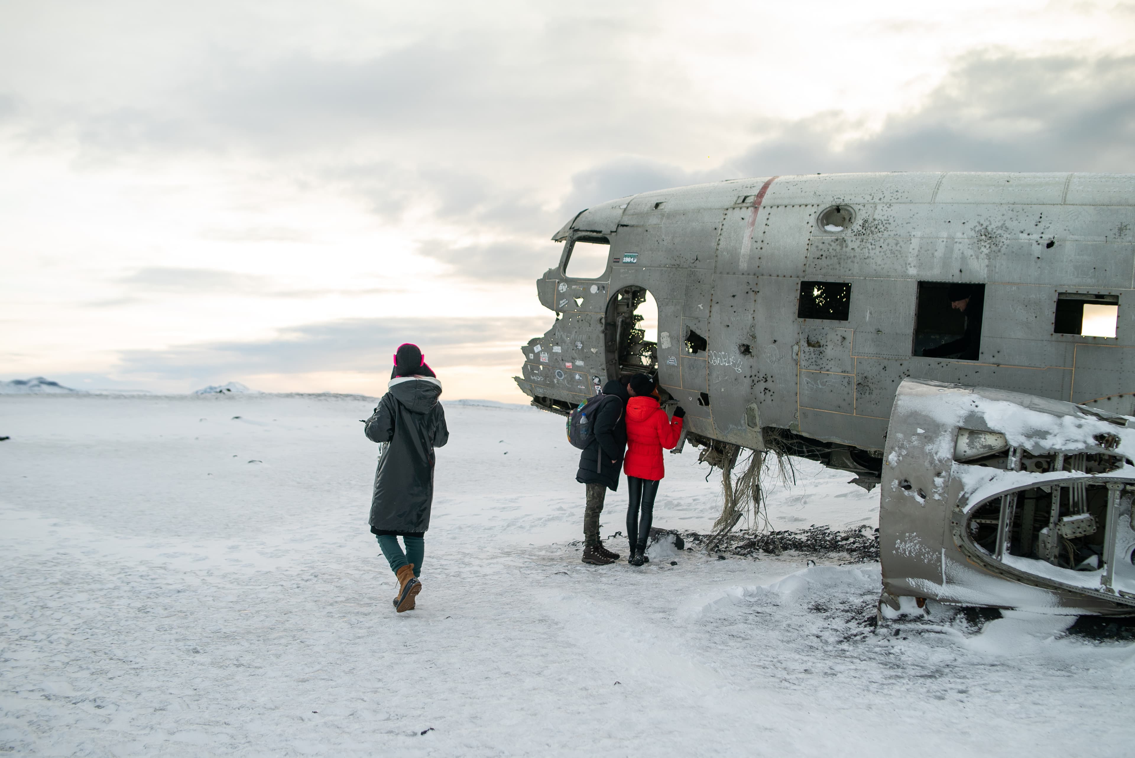 a group of friends goes through a snowy field to a crashed plane in Iceland