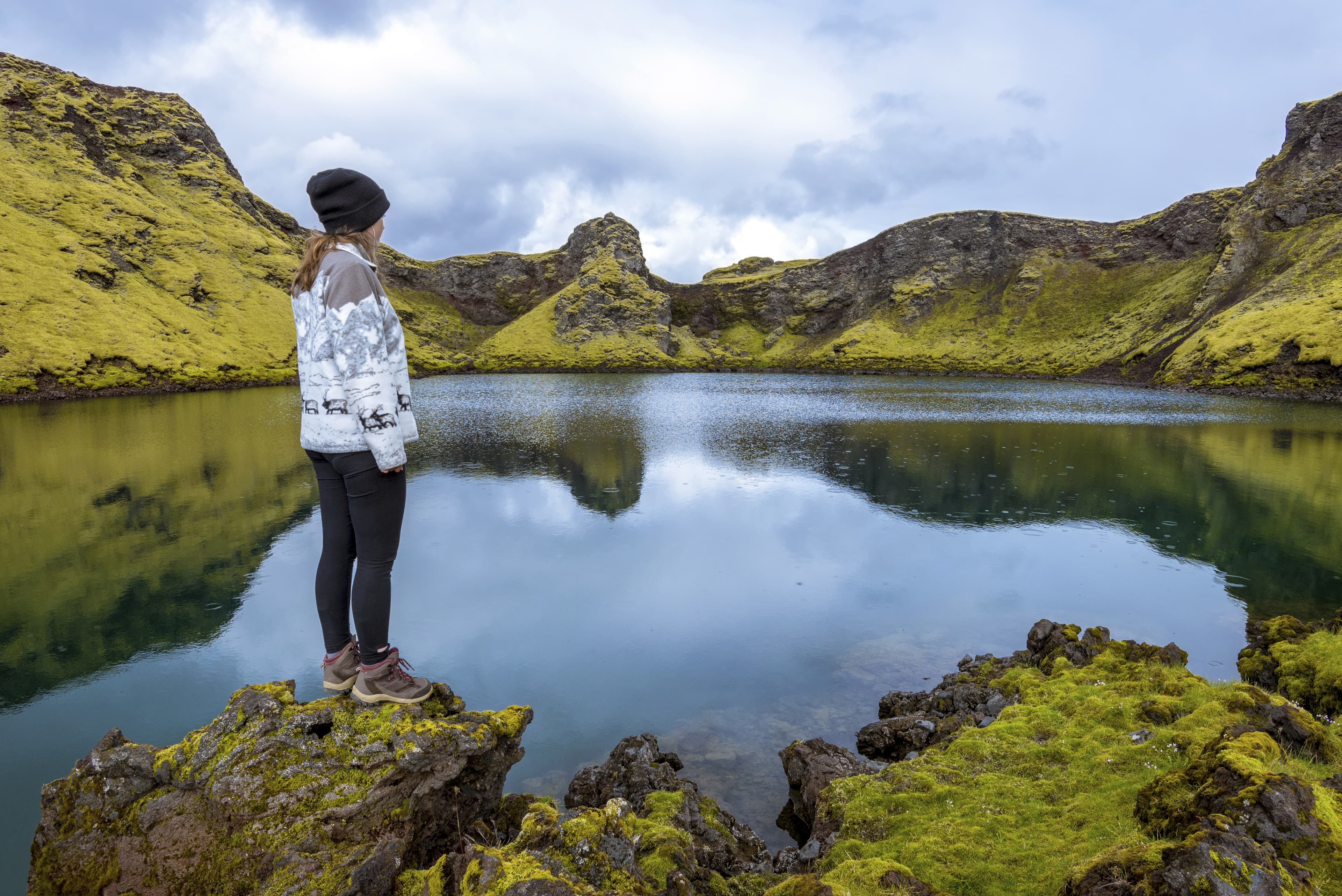 Girl teenager is staying in the border of the pond in the crater Tjarnargigur, one of most impressive craters of Lakagigar volcanic fissure area in Southern highlands of Iceland. Girl teenager is staying in the border of the pond in the crater Tjarnargigur, one of most impressive craters of Lakagigar volcanic fissure area in Southern highlands of Iceland.