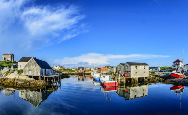 A calm summer evening in the fishing village of Peggys Cove, Nova Scotia. Local buildings and boats cast mirror like reflections in the near still Atlantic Ocean. July 24, 2016...Camera: Nikon D3300 & Bower 8mm fisheye lens..http://kenmo.fineartamerica.com/.http://kenmo.zenfolio.com/ The Best of Halifax Tour with Peggy's Cove 1