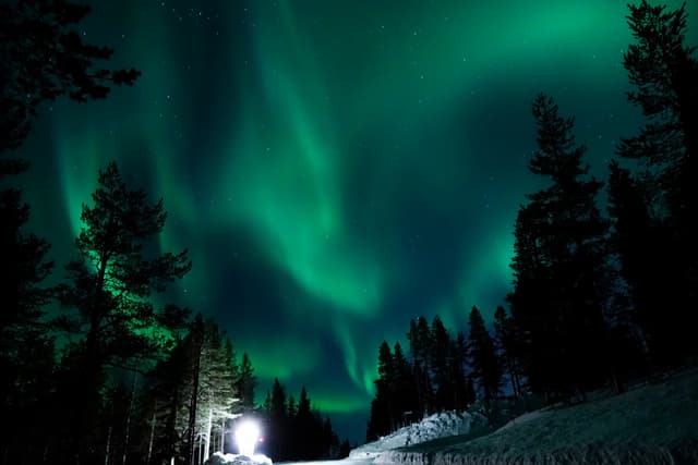 Large lamp illuminating the countryside for tourists to observe aurora borealis.