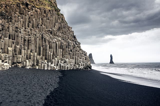 The black sand beach of Reynisfjara and the mount Reynisfjall from the Dyrholaey promontory in the southern coast of Iceland. The black sand beach of Reynisfjara in Iceland