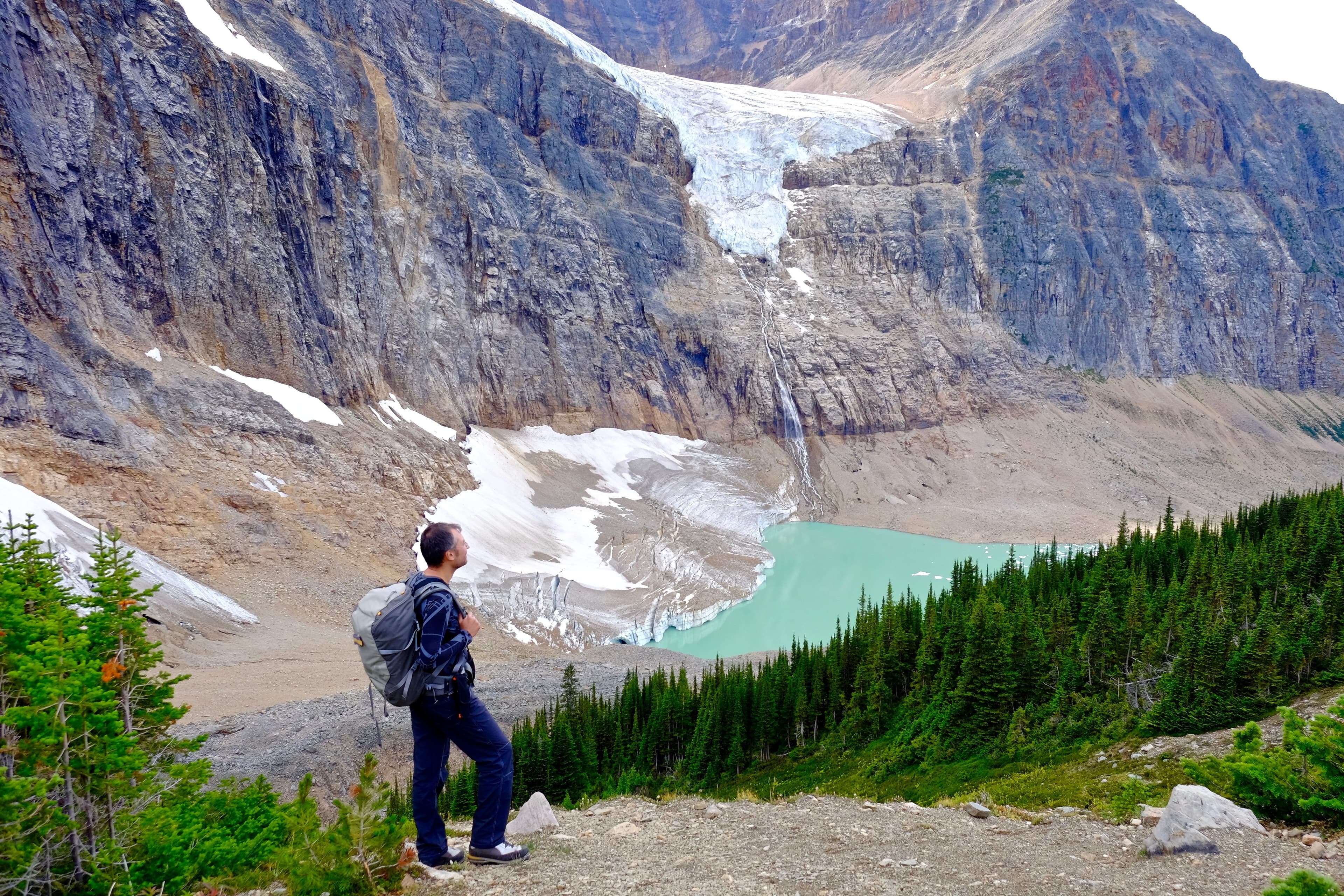Canada. Man hiker stainding on rocks by glacier lake.