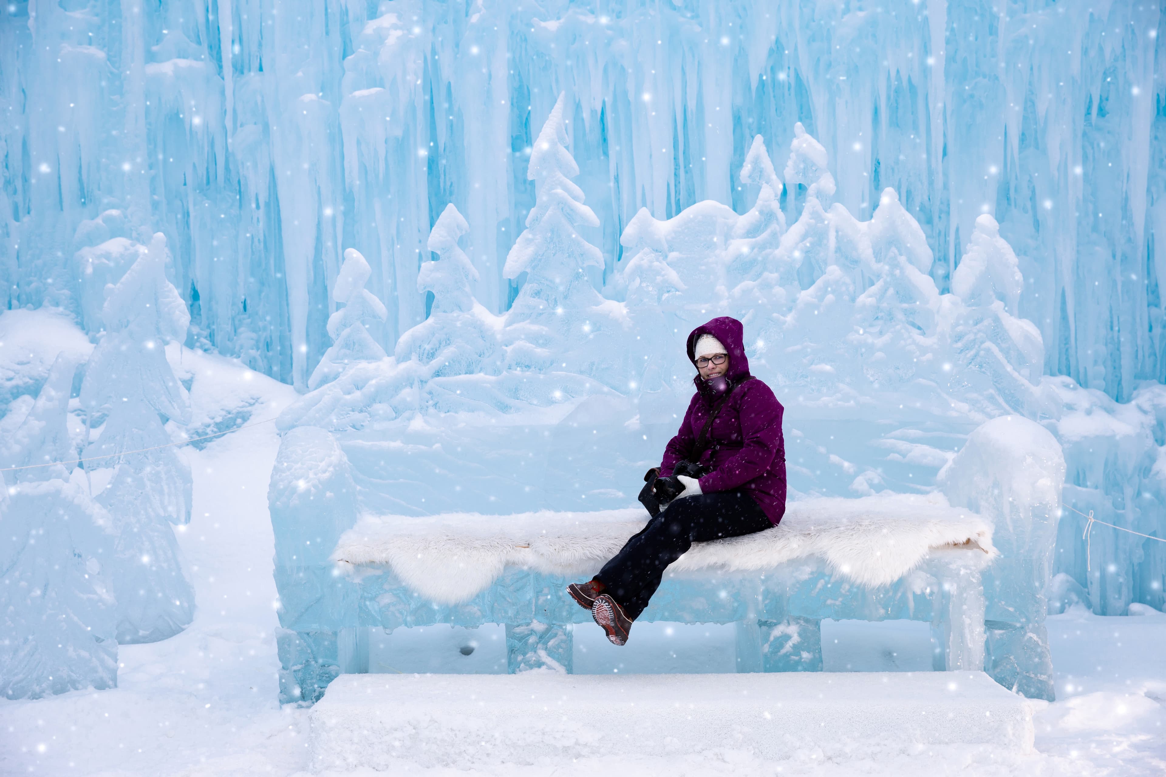 horizontal image of a caucasian woman on vacation sitting on an ice bench at the ice castles in the winter time. woman sitting on an ice bench at the ice castles