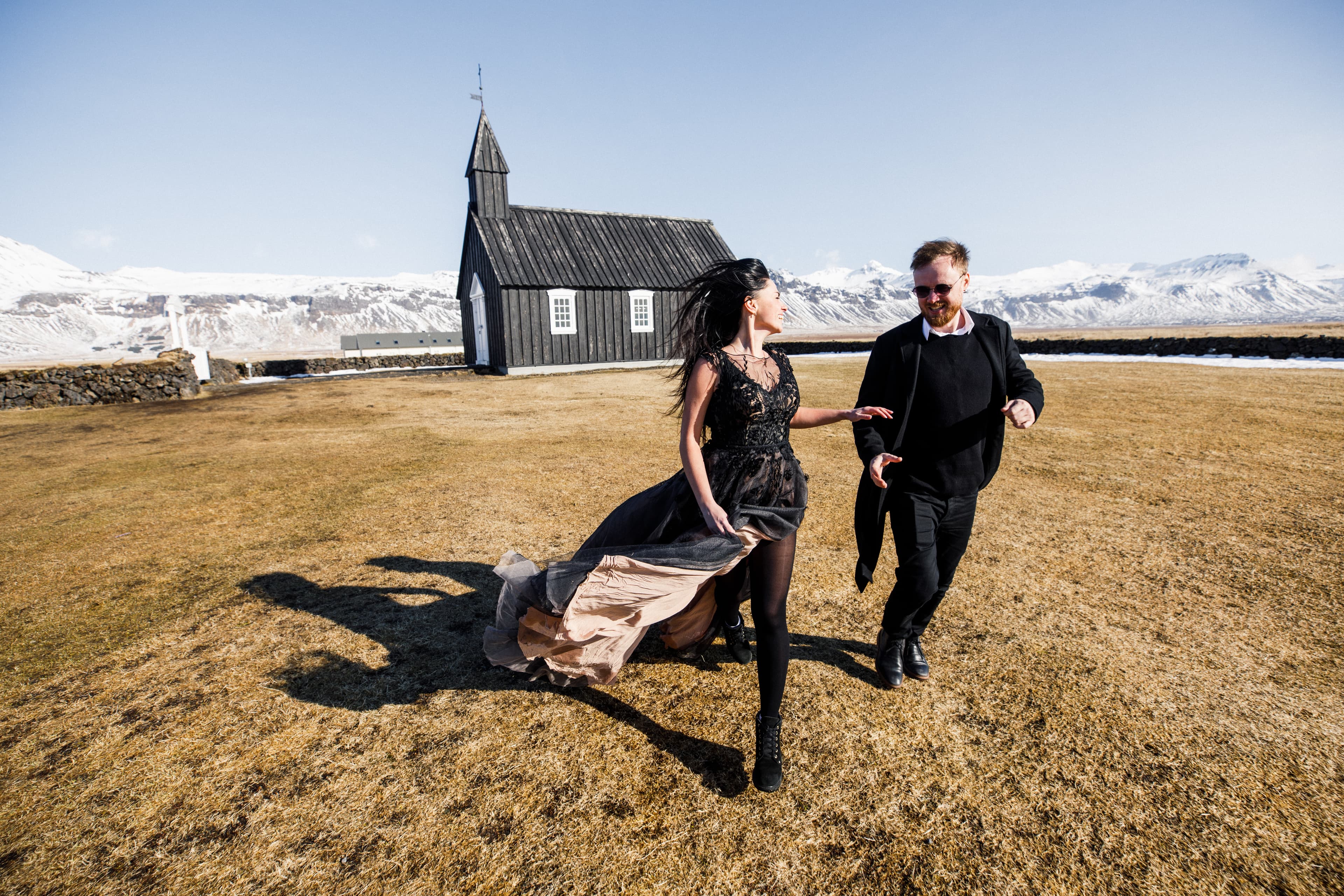 Young beautiful couple bride and groom in black clothes walks near a black church in Iceland