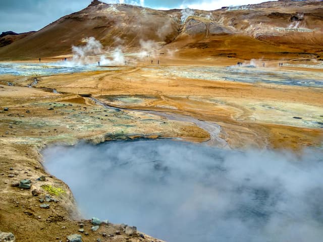 Iceland. Tourists walk around the turmal springs. Steam rises above the hot springs. Iceland. Tourists walk around the turmal springs. Steam rises above the hot springs.